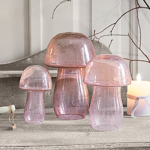 Drei dekorative Pilze aus rosa Glas auf grauer Oberfläche, stilvolle Wohnraumdeko