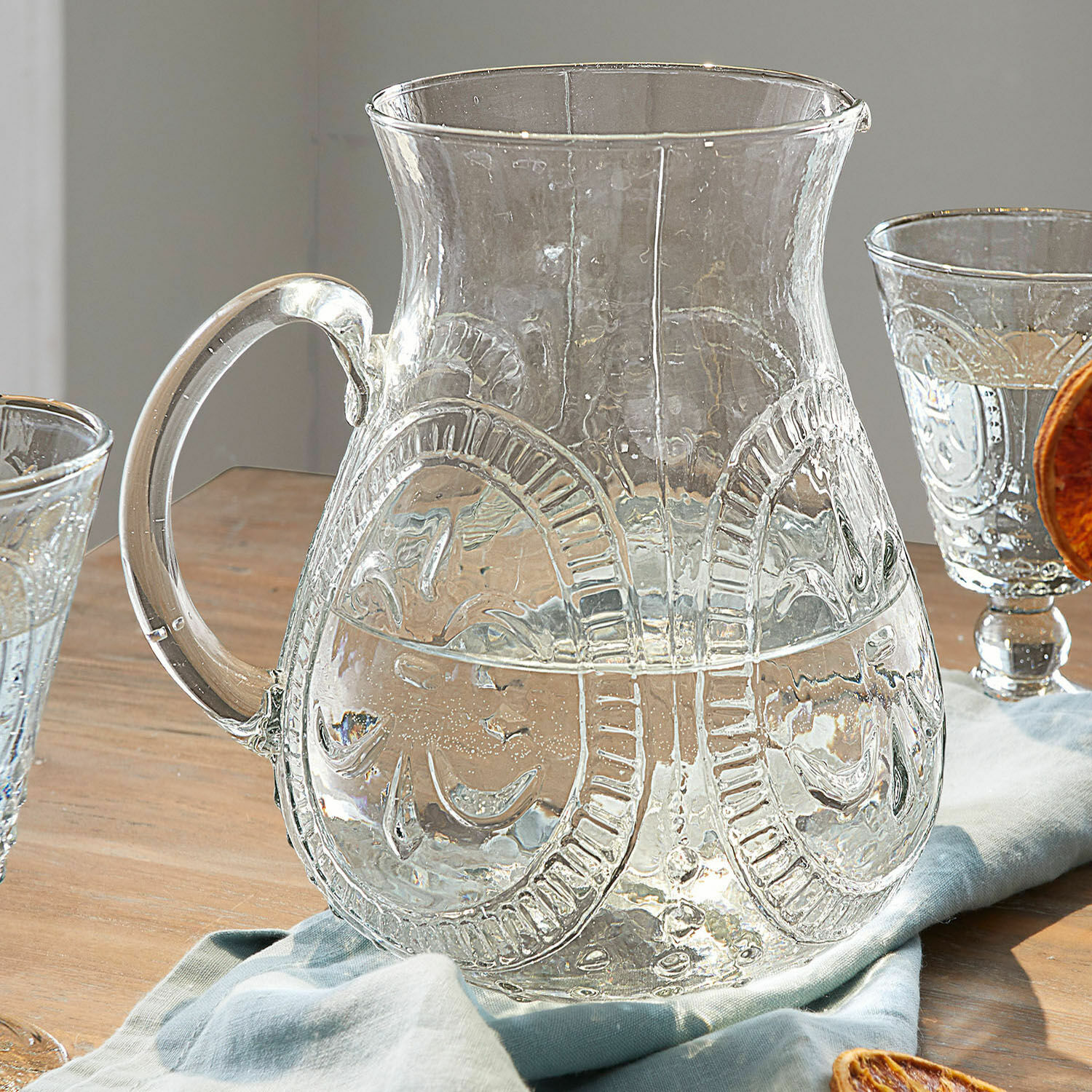 Krug Pépin Transparenter Glas-Krug mit dekorativem Muster auf Holztisch mit Stoffserviette