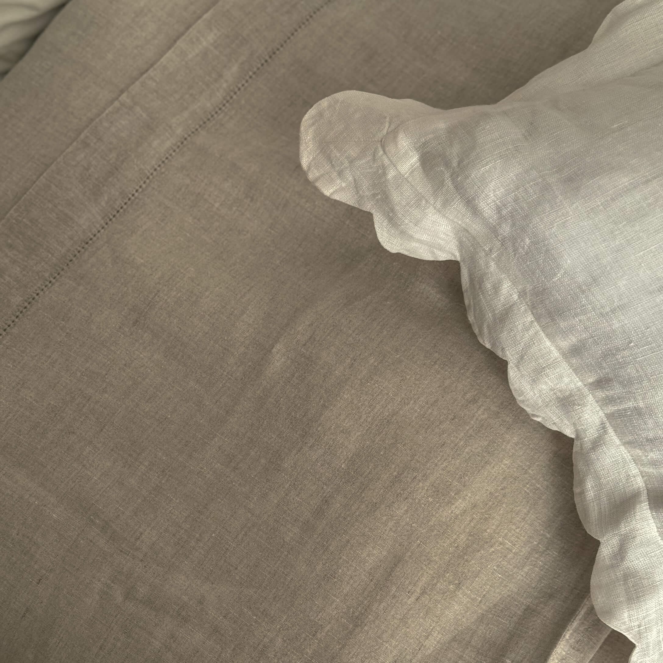 Beige Leinenbettwäsche mit weissem Rüschensaum, natürliche Stoffqualität für ein gemütliches Schlafzimmer