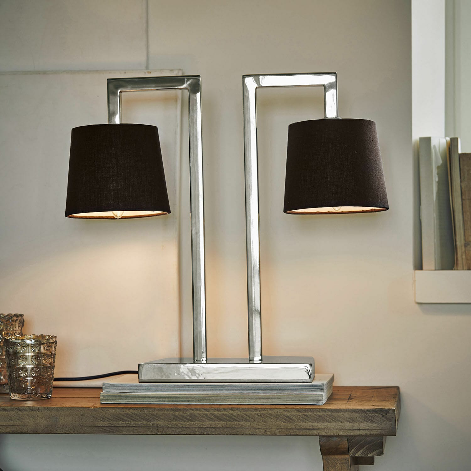 Moderne Tischlampe mit Metallfuss und zwei schwarzen Lampenschirmen auf Holztisch