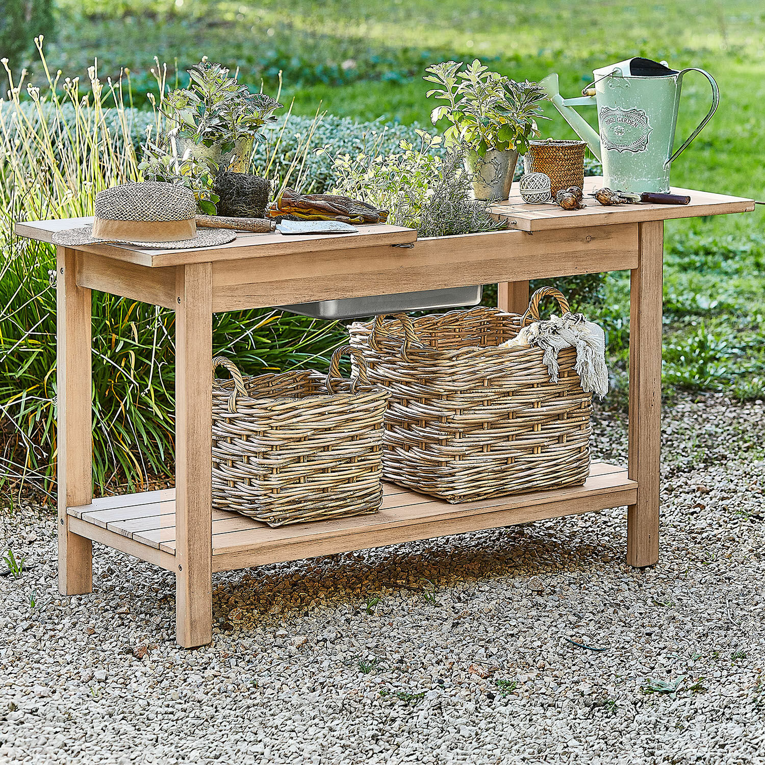 Pflanztisch FSC®-100% Venzone Gartentisch aus Holz mit Blumentöpfen, grüner Giesskanne und Weidenkörben auf Kiesboden