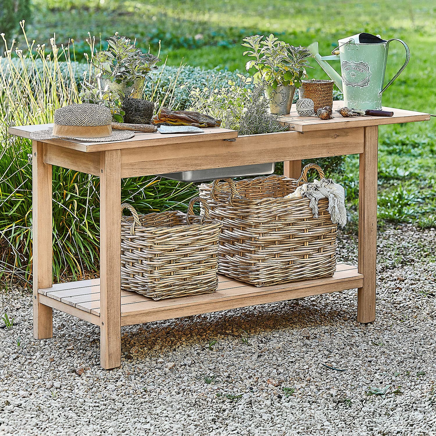 Pflanztisch FSC®-100% Venzone Gartentisch aus Holz mit Blumentöpfen, grüner Giesskanne und Weidenkörben auf Kiesboden