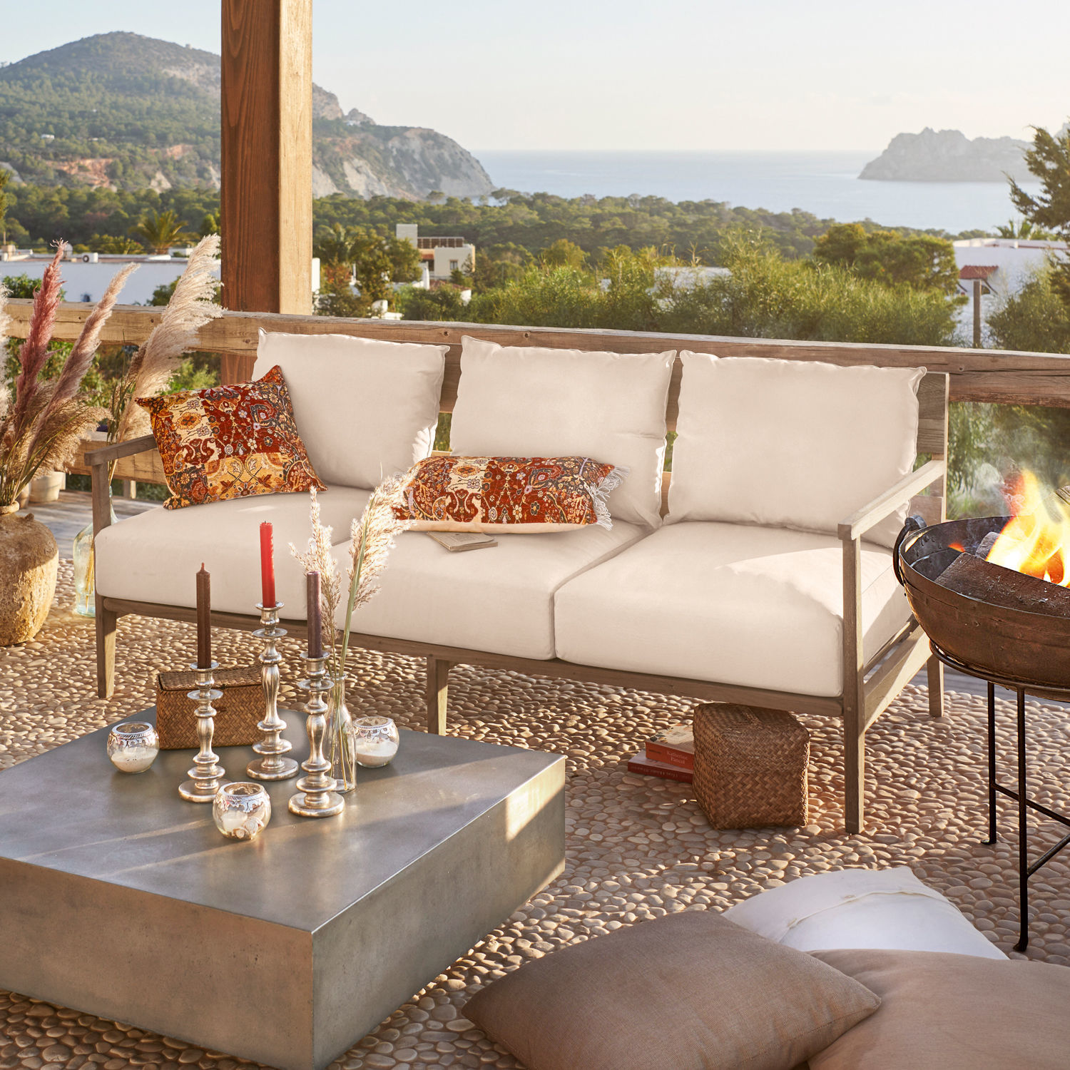 Sofa Kingsbridge Beiges Outdoor-Sofa mit Holzrahmen und bunten Kissen auf Terrasse mit Meerblick