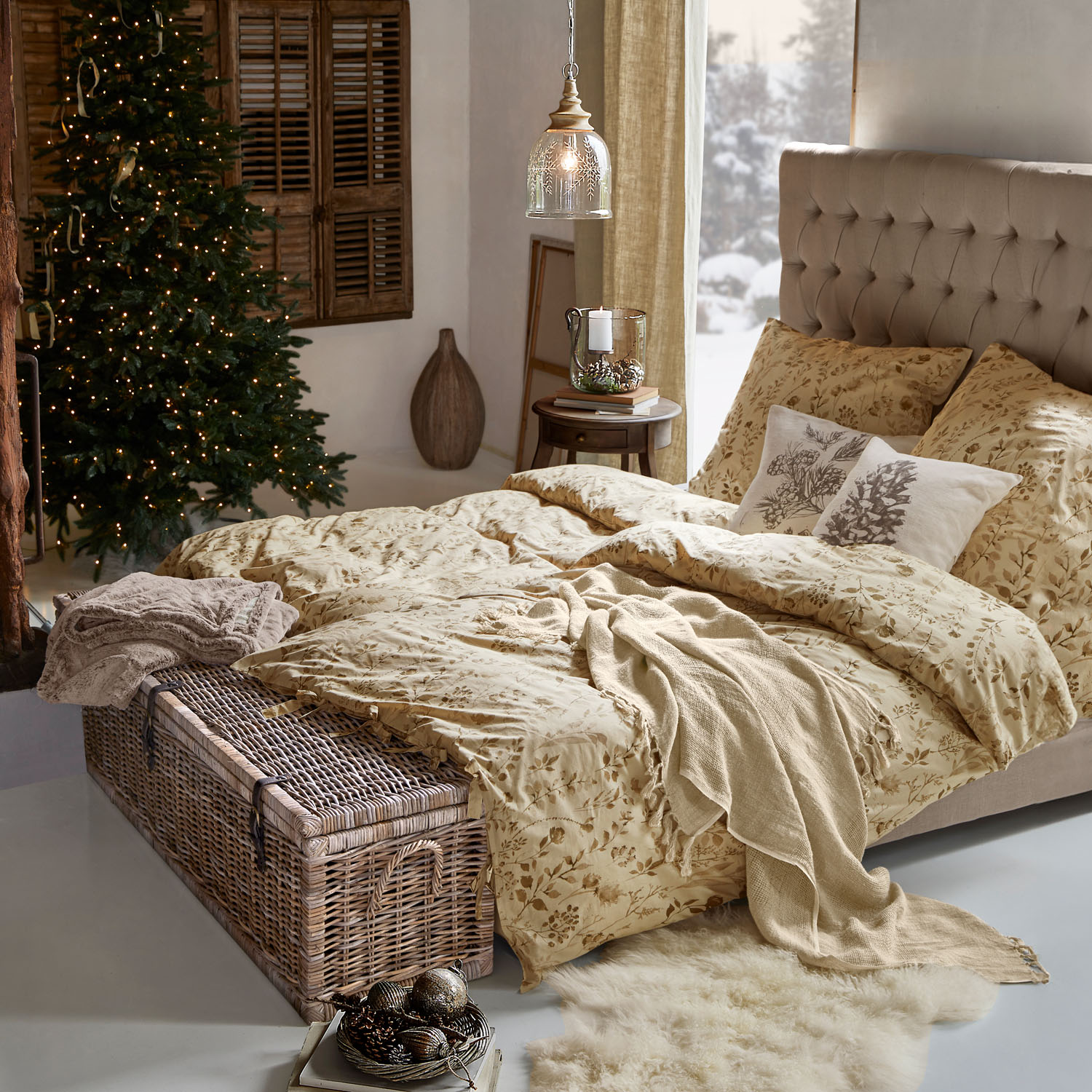 Gemütliches Schlafzimmer mit beiger Bettwäsche mit Blumenmuster und Korbtruhe am Fussende