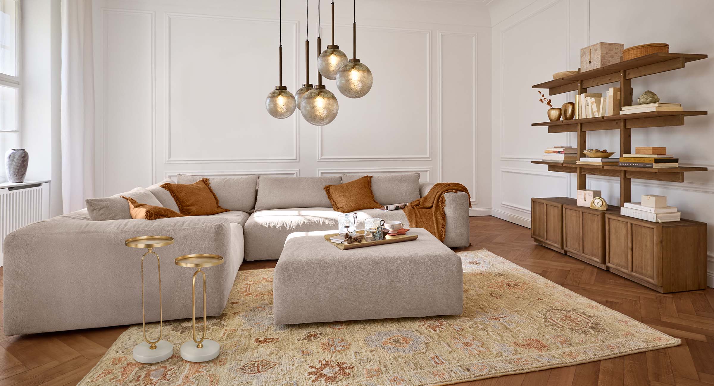 Gemütliches Wohnzimmer mit beigem Sofa, braunen Kissen und Holzregal in natürlichen Farbtönen