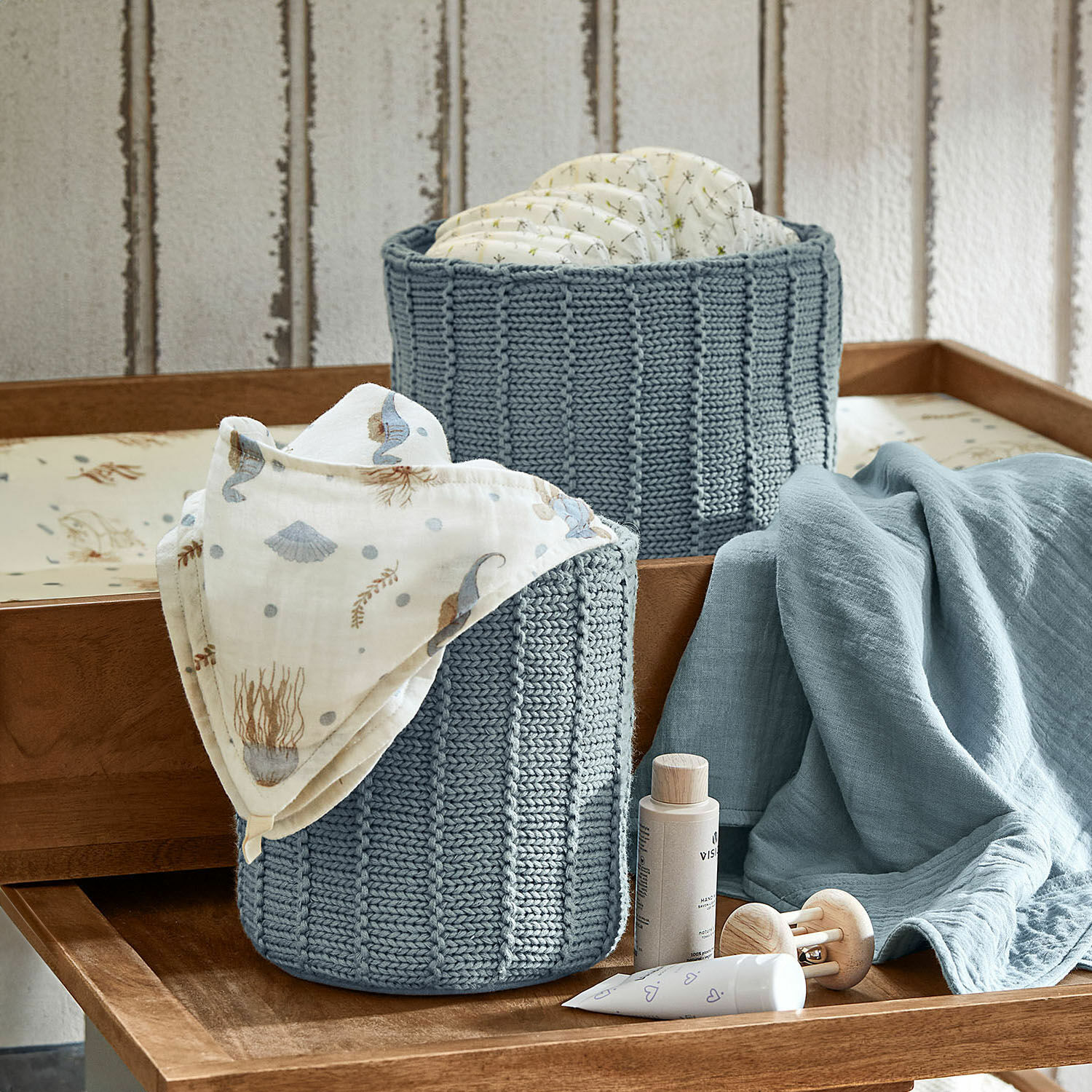 Box 2er Set Fiorenzo Zwei blaue, gestrickte Körbe für Windeln und Babyzubehör auf einem Holzwickeltisch
