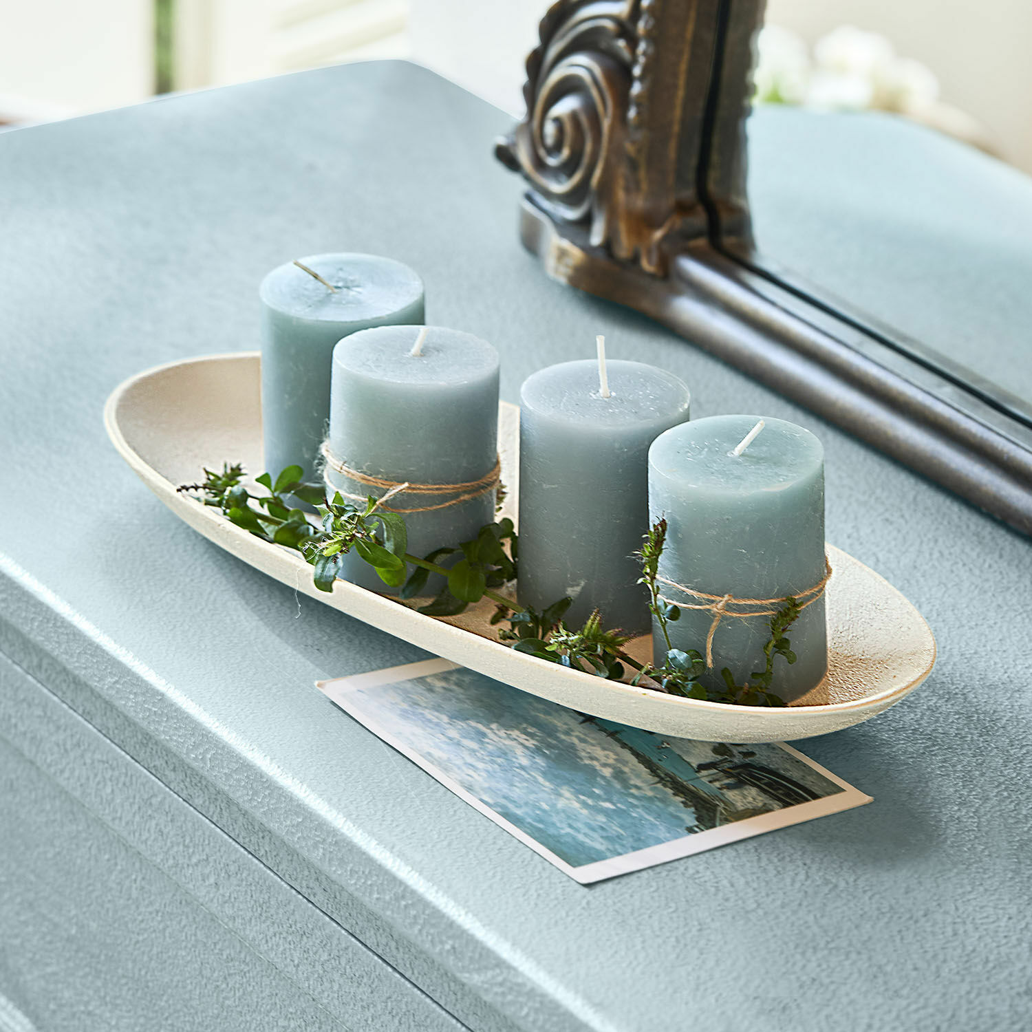 Schale Cantresse Vier blaue Kerzen mit grünen Blättern auf einem beigen Tablett auf einem Tisch arrangiert