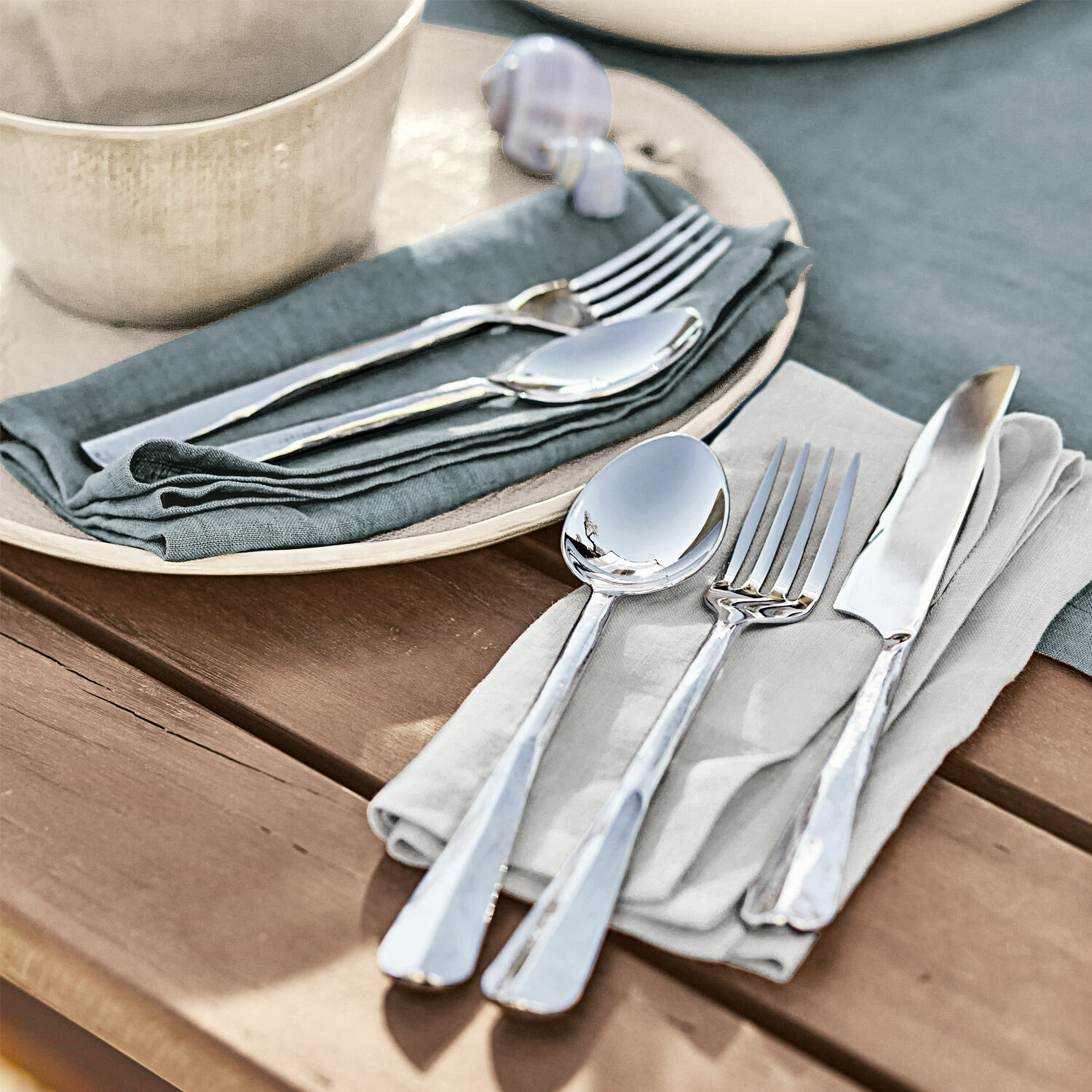 Besteck Malden Set aus silbernem Edelstahlbesteck auf Leinenservietten auf einem Holztisch