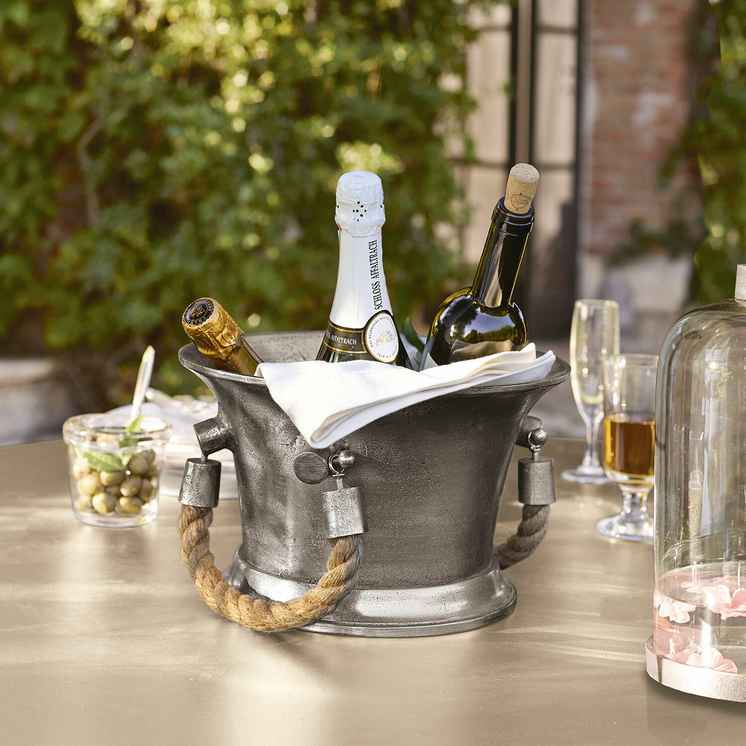 Metall-Eisbehälter mit Seilgriffen zum Kühlen von Wein- und Champagnerflaschen auf dem Tisch
