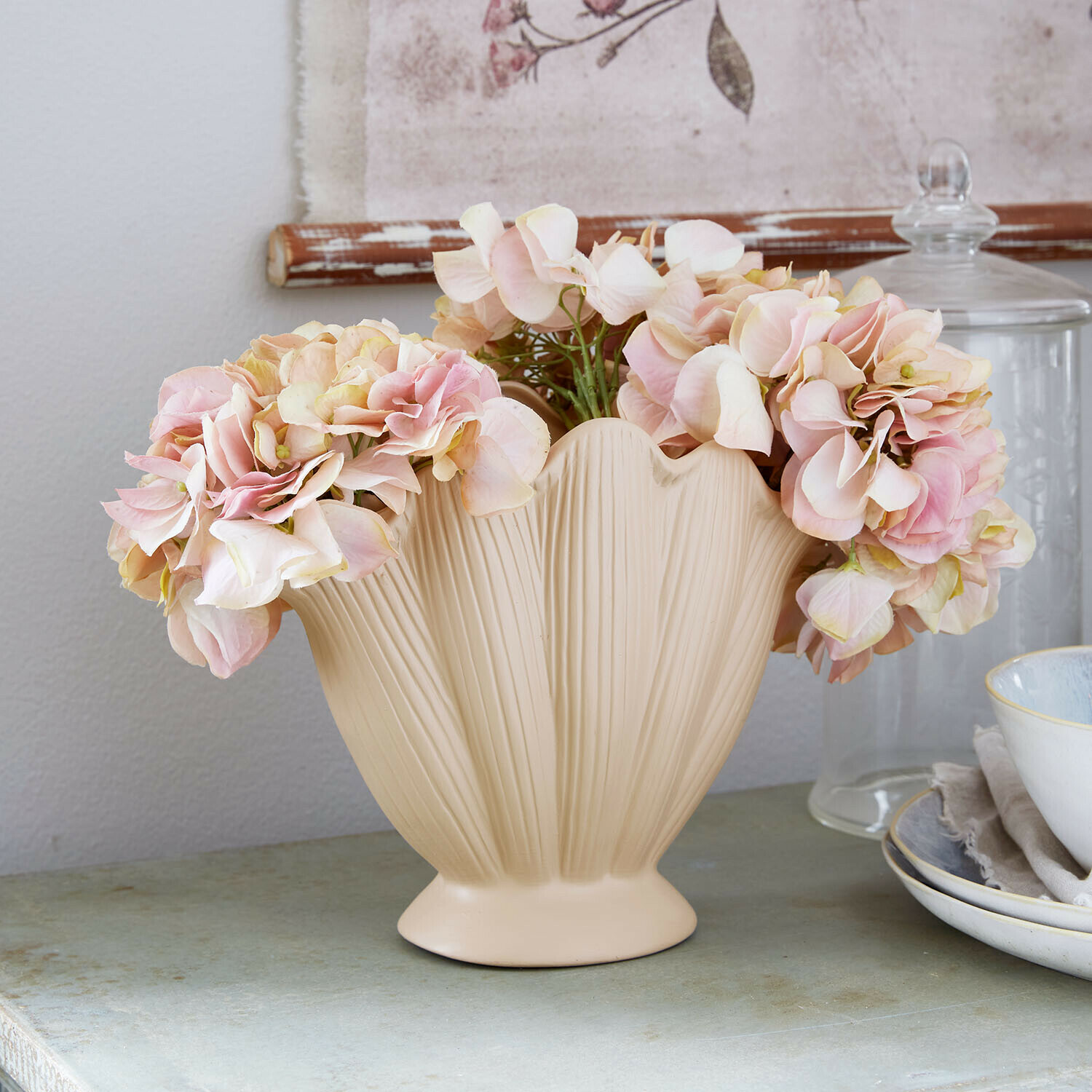 Vase Nuvienne Beige Keramikvase mit Blattstruktur und rosa Dekoblumen auf einem Tisch