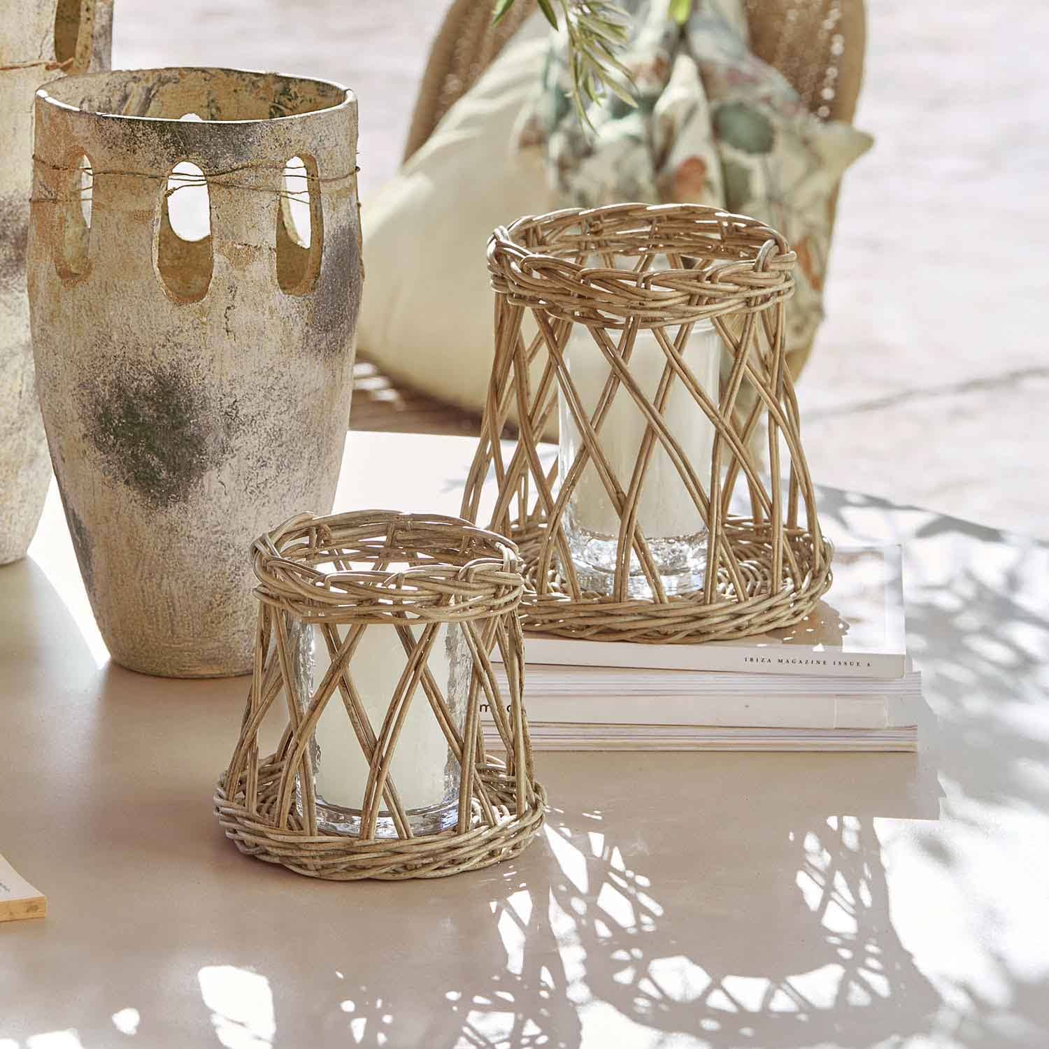 Zwei Windlichter aus natürlichem Rattan mit weissen Kerzen auf hellem Tisch, Wohnaccessoire