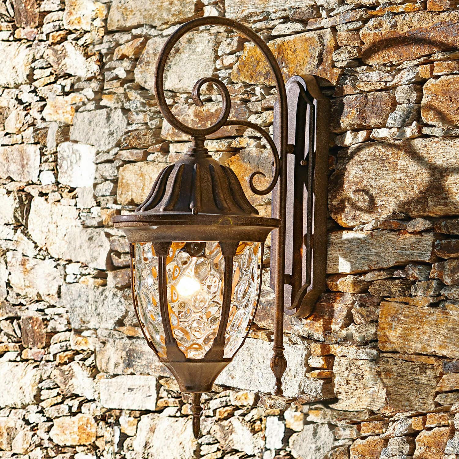Aussenwandlampe Herrère Rustikale Wandlampe aus rostigem Metall mit dekorativem Glas an einer Steinmauer