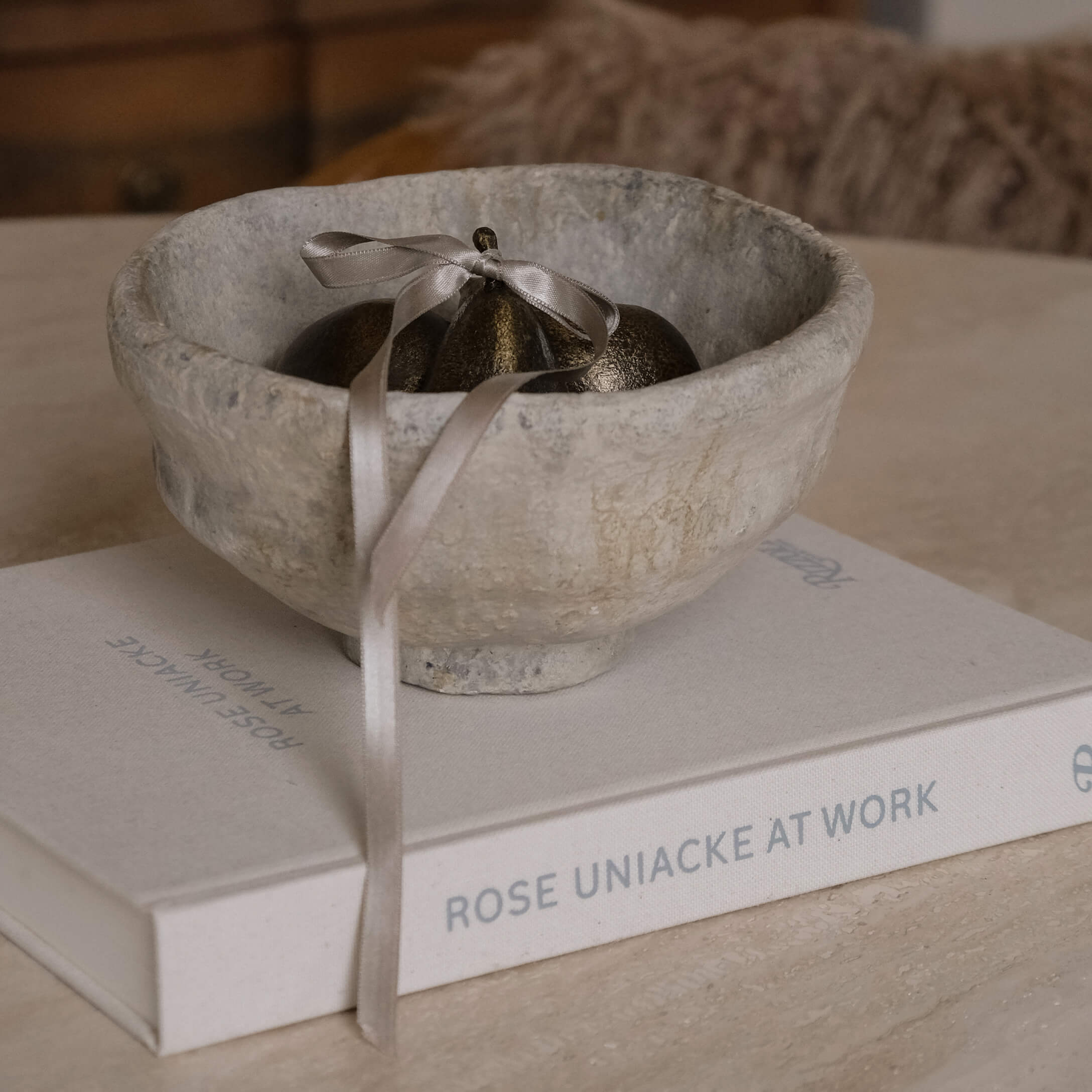 Dekorative graue Steinschale mit Metallornament und Band auf einem Buch auf dem Tisch