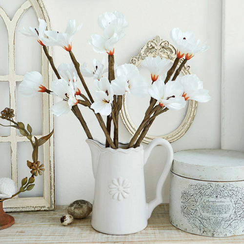 Weisser Keramikkrug mit dekorativen weissen Blumen auf Holztisch, Vintage-Stil, Wohnaccessoire