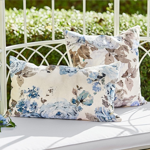 Dekorative Kissen mit blau-beigem Blumenmuster auf weisser Gartenbank aus Metall