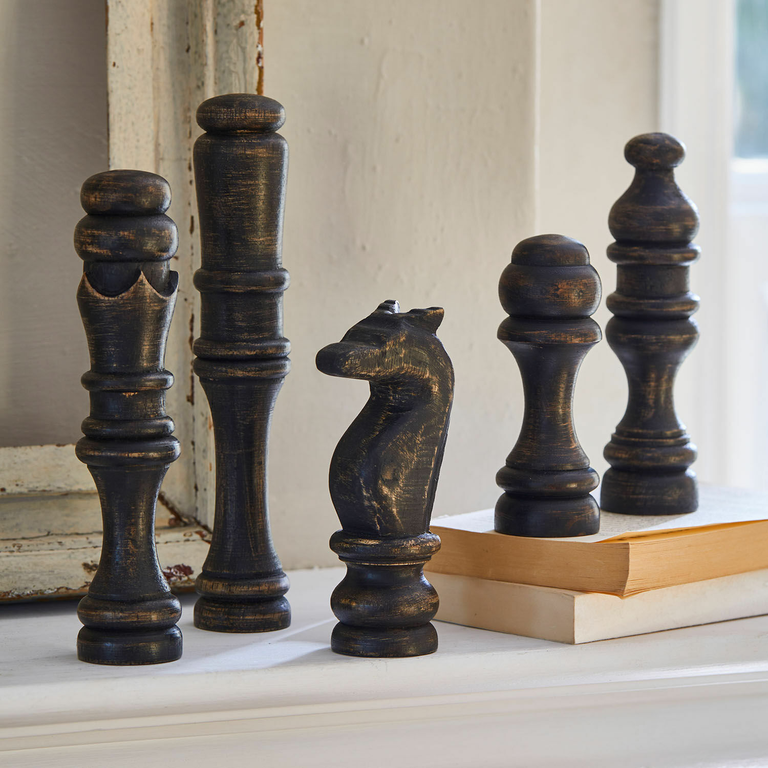Deko-Objekt 5er Set Guillemineau Dekorative schwarze Schachfiguren aus Holz mit antikem Finish auf einem Regal neben Büchern.