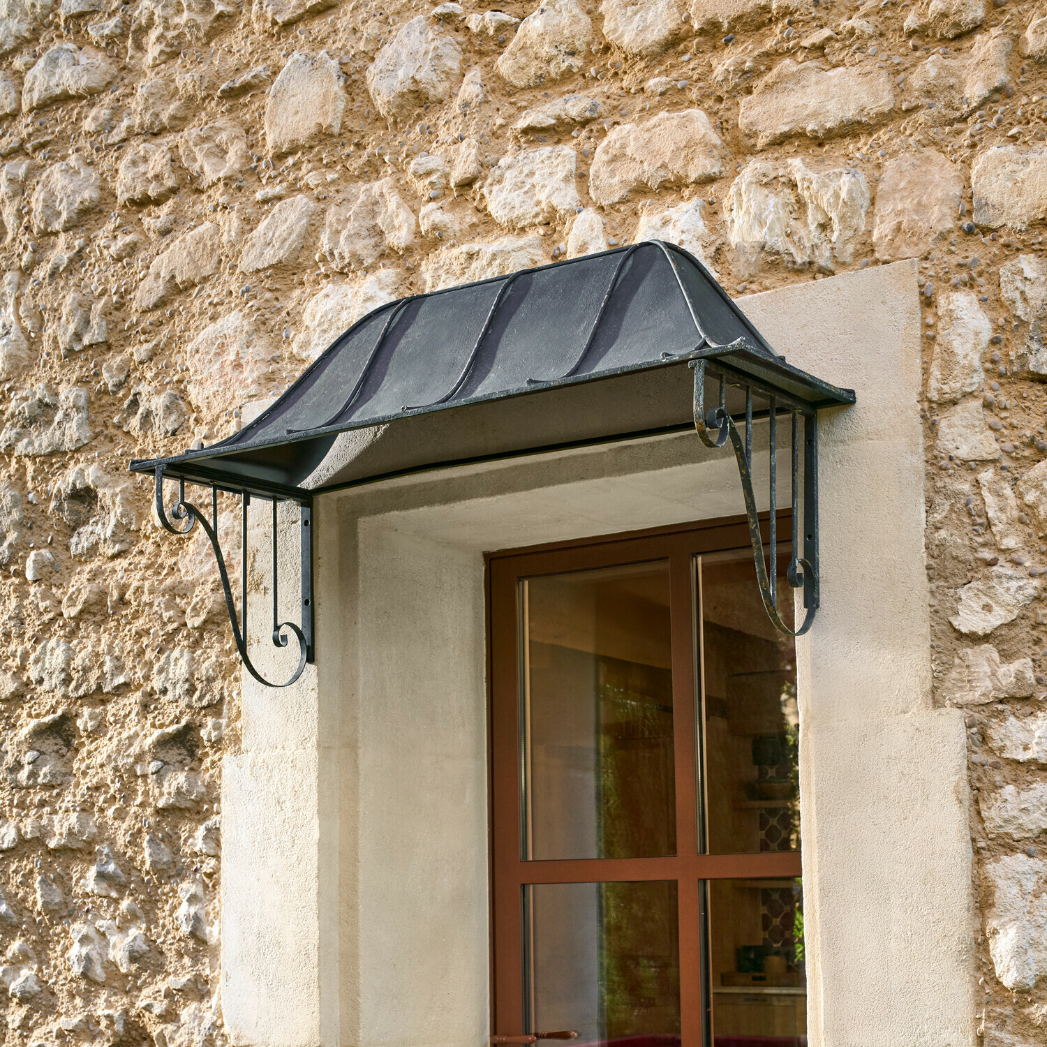 Schwarzes Metallvordach über Fenster an Steinmauer, Schutz vor Regen und Witterung