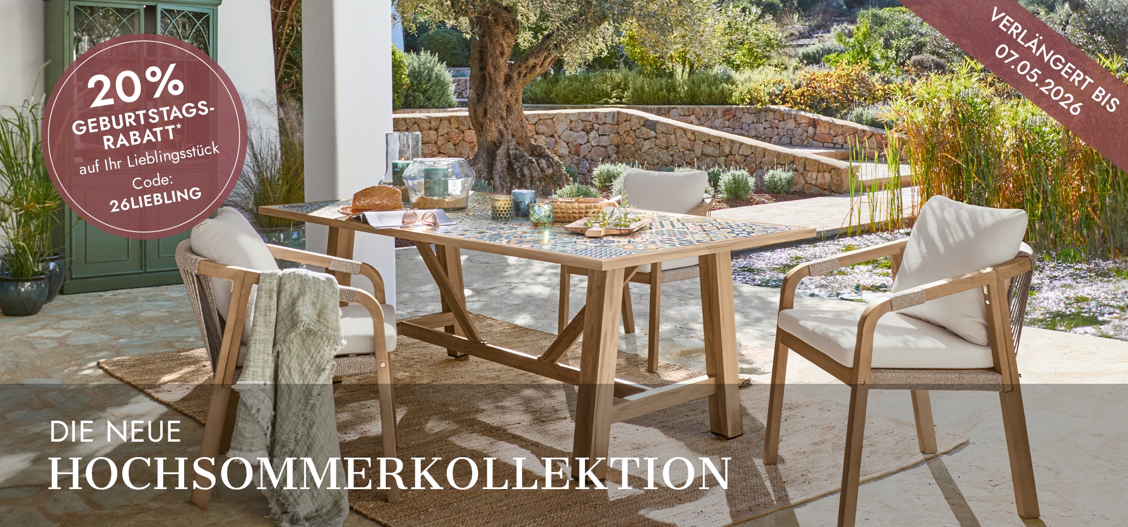 Gartenmöbel-Set mit Holztisch und cremefarbenen Polstern auf Terrasse in sonnigem Garten