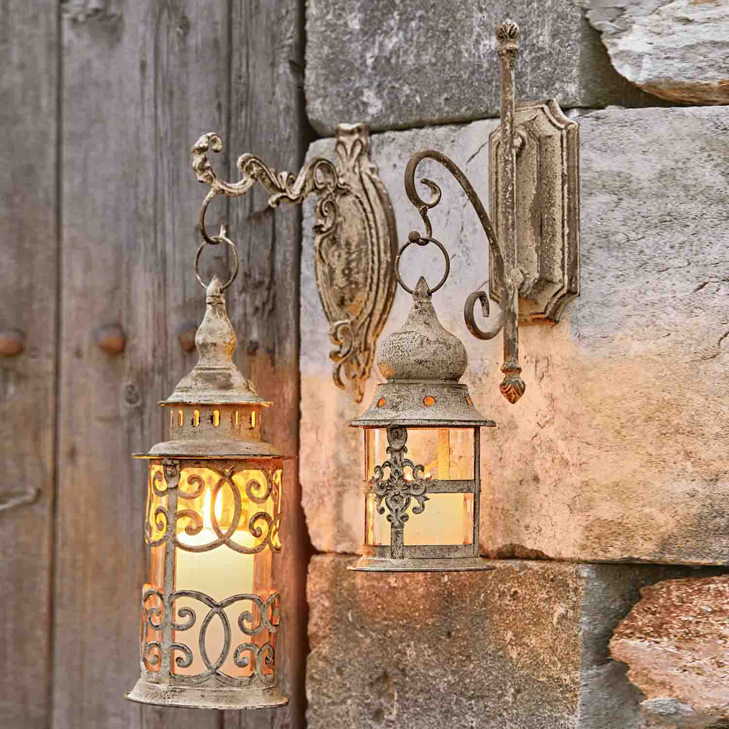 Zwei rustikale Wandlampen aus Metall in gealtertem Beige, beleuchten eine Steinwand im Vintage-Stil