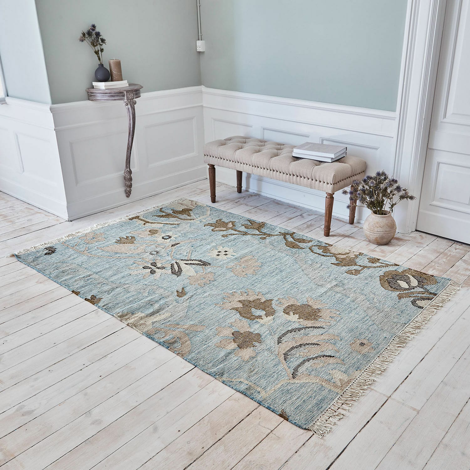 Teppich Nére Baumwollteppich in Blau und Beige mit floralem Muster auf hellem Holzboden im Wohnzimmer