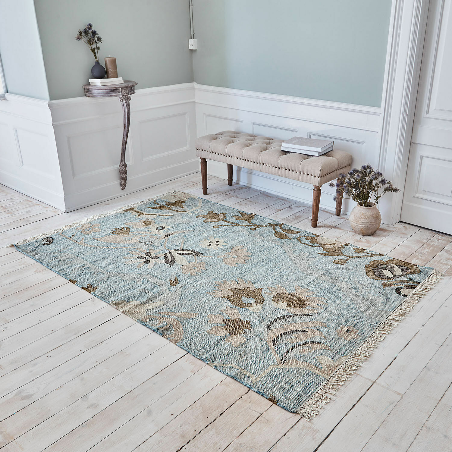 Teppich Nére Baumwollteppich in Blau und Beige mit floralem Muster auf hellem Holzboden im Wohnzimmer