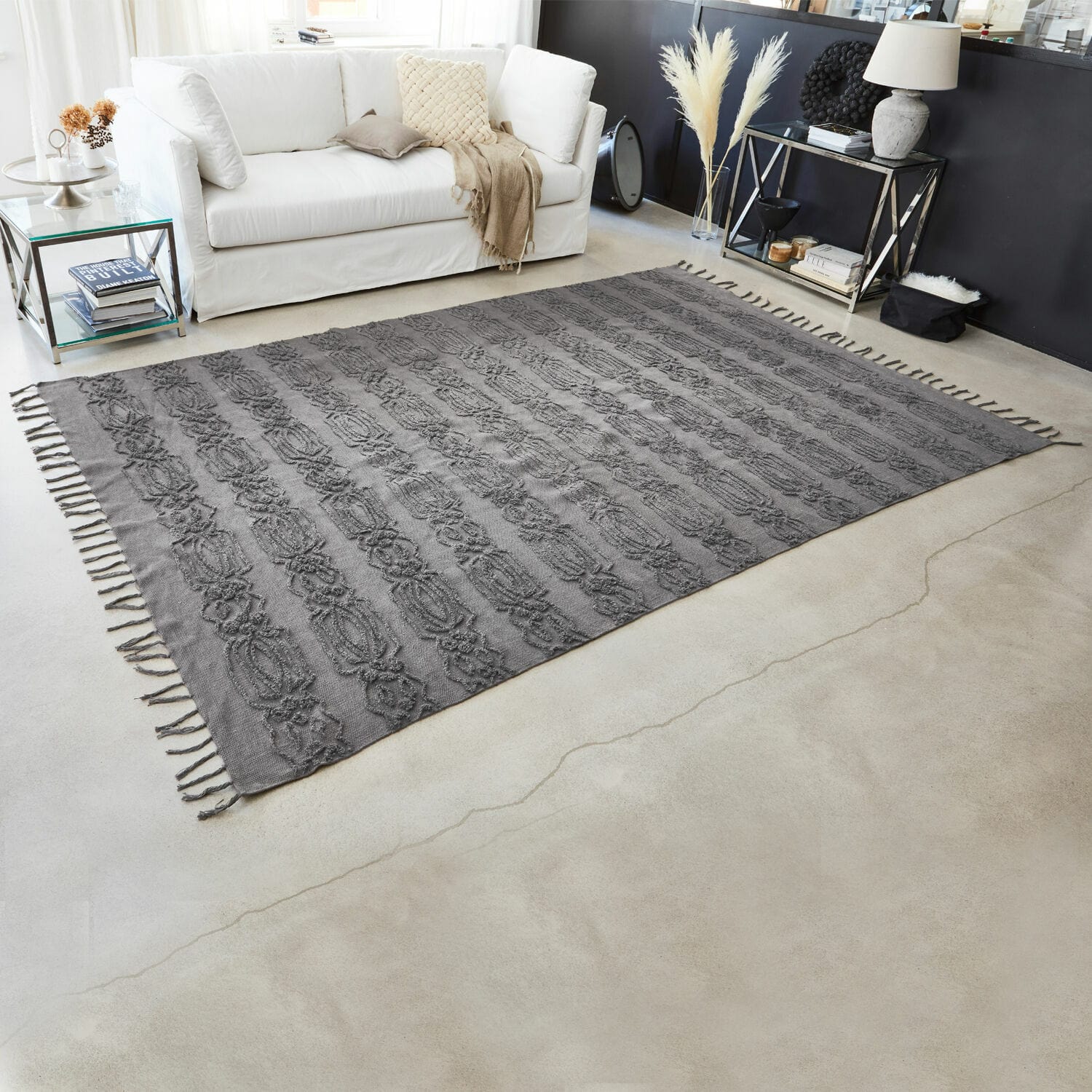 Grauer Baumwollteppich mit dekorativem Muster und Fransen im modernen Wohnzimmer mit weissem Sofa