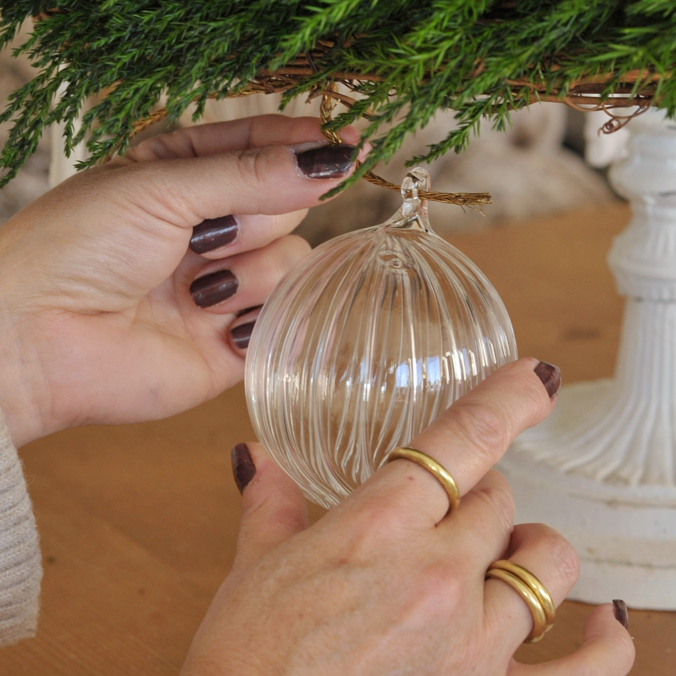 Transparente Glas-Weihnachtskugel mit Rillen an grüner Tannenzweig-Dekoration hängend