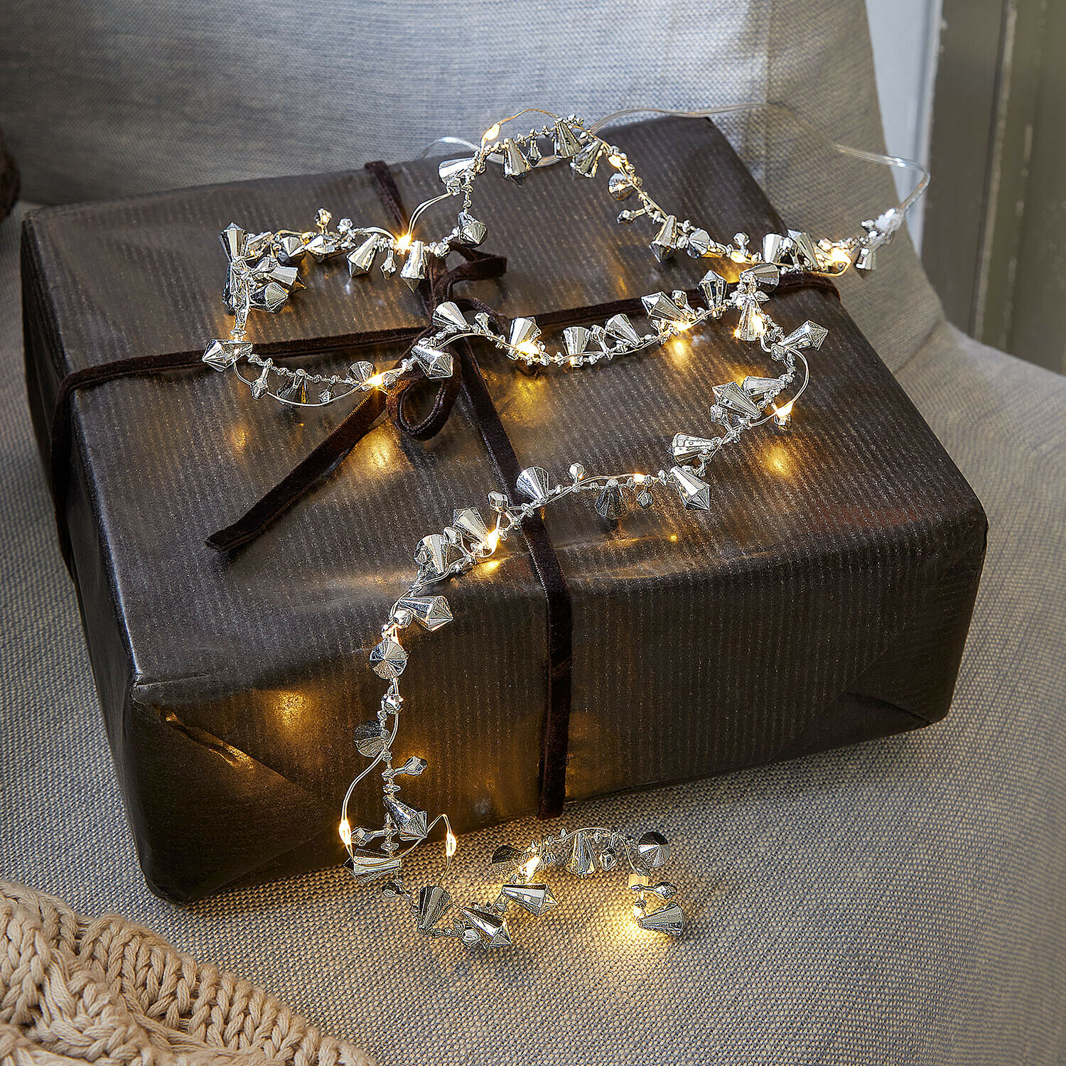 Lichterkette Bryesa Feine Lichterkette mit silbernen Metallanhängern auf dunklem Geschenkpaket dekorativ drapiert