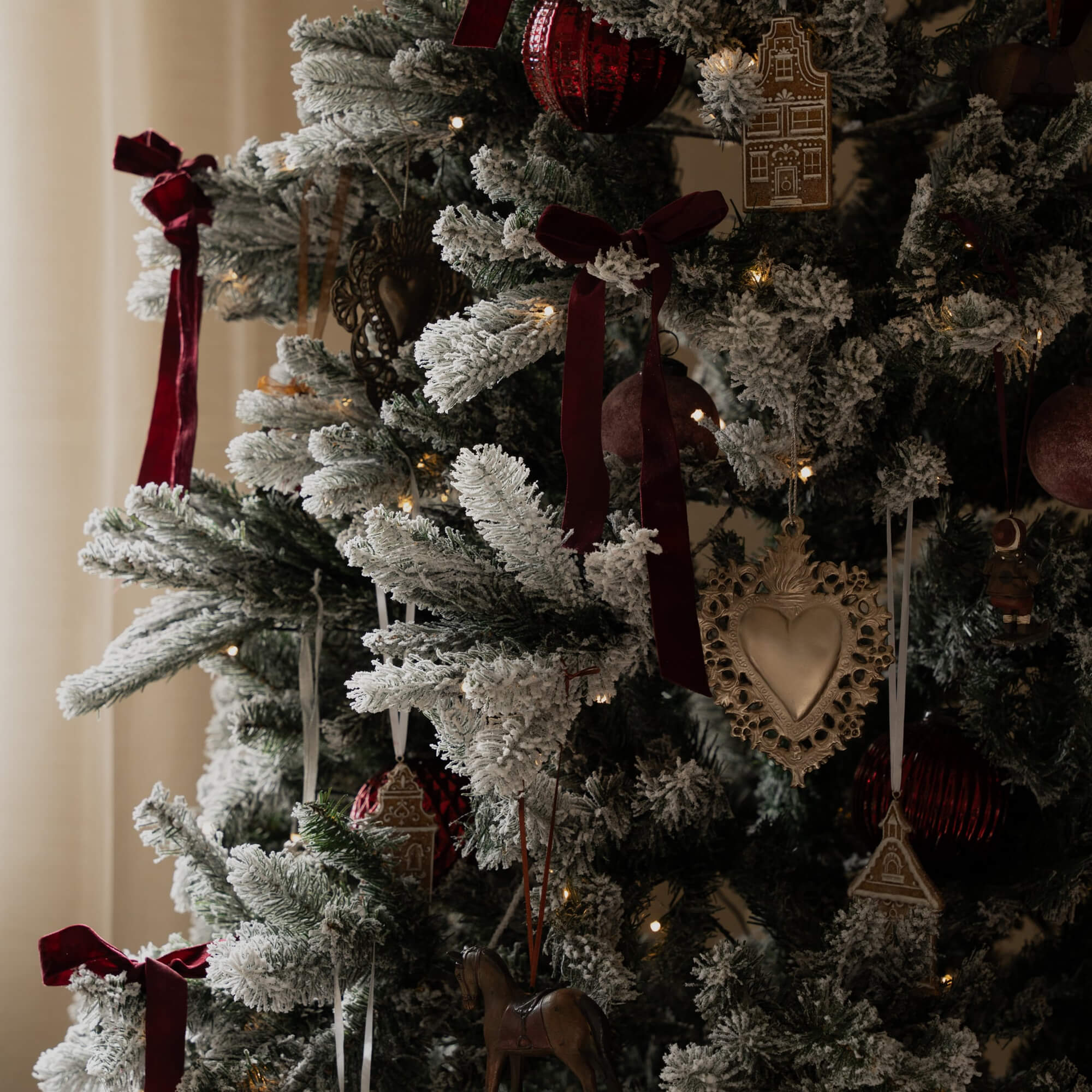 Künstlicher Weihnachtsbaum mit weissem Schneeeffekt, roten Samtbändern und traditionellem Christbaumschmuck