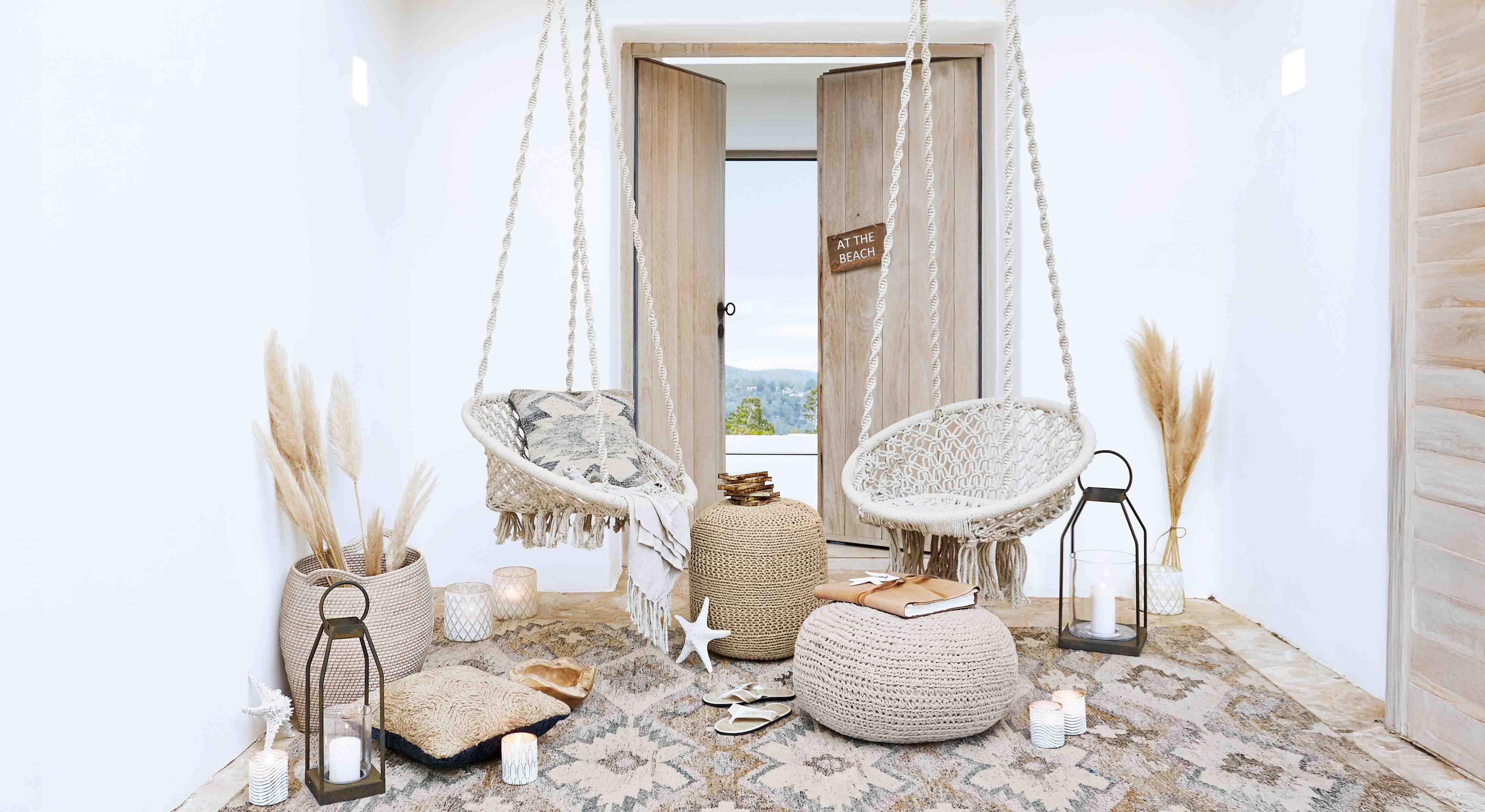 Gemütliches Wohnzimmer mit weissen Makramee-Hängesesseln und natürlichen Boho-Dekorationen