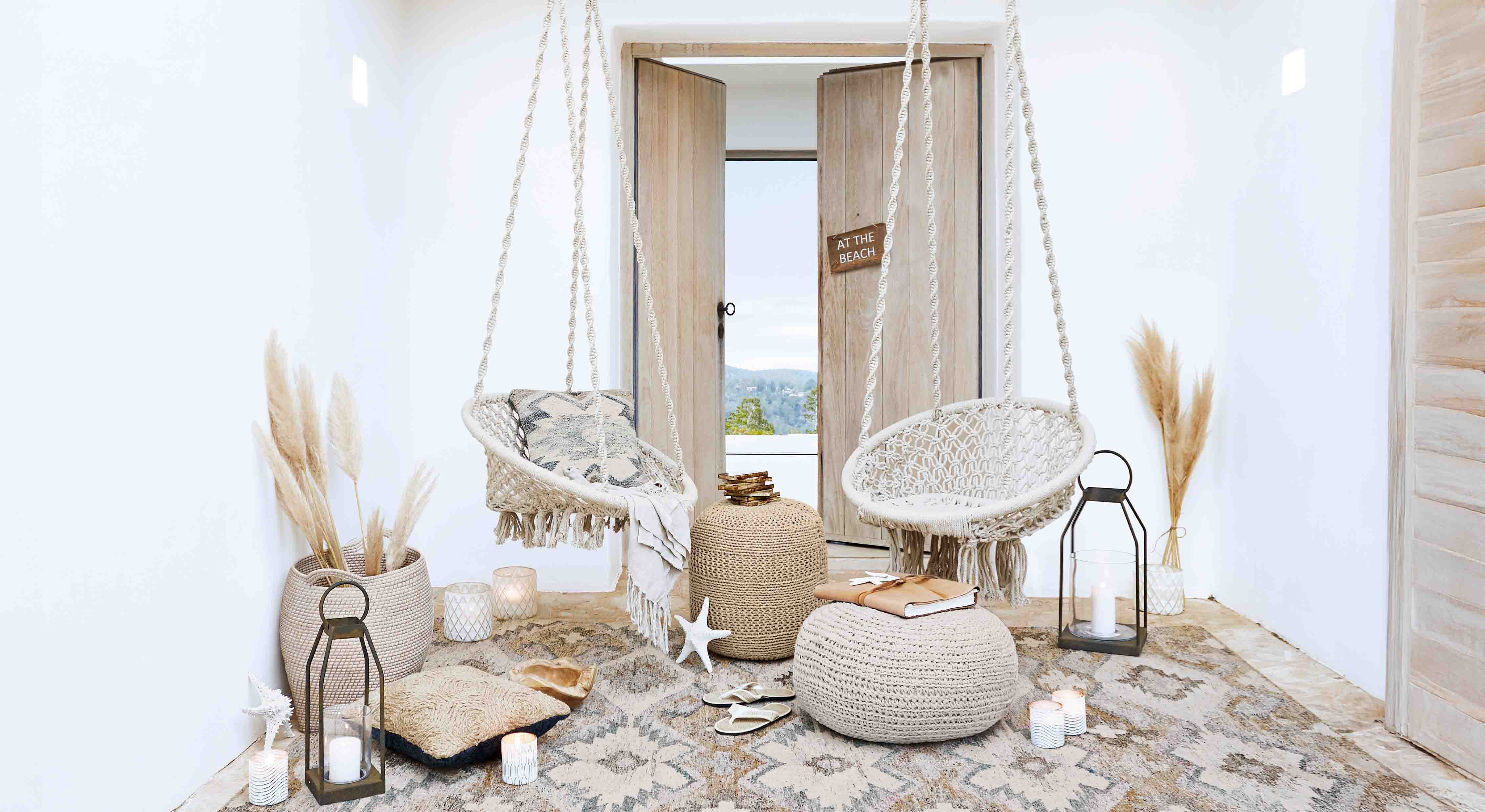 Gemütliches Wohnzimmer mit weissen Makramee-Hängesesseln und natürlichen Boho-Dekorationen