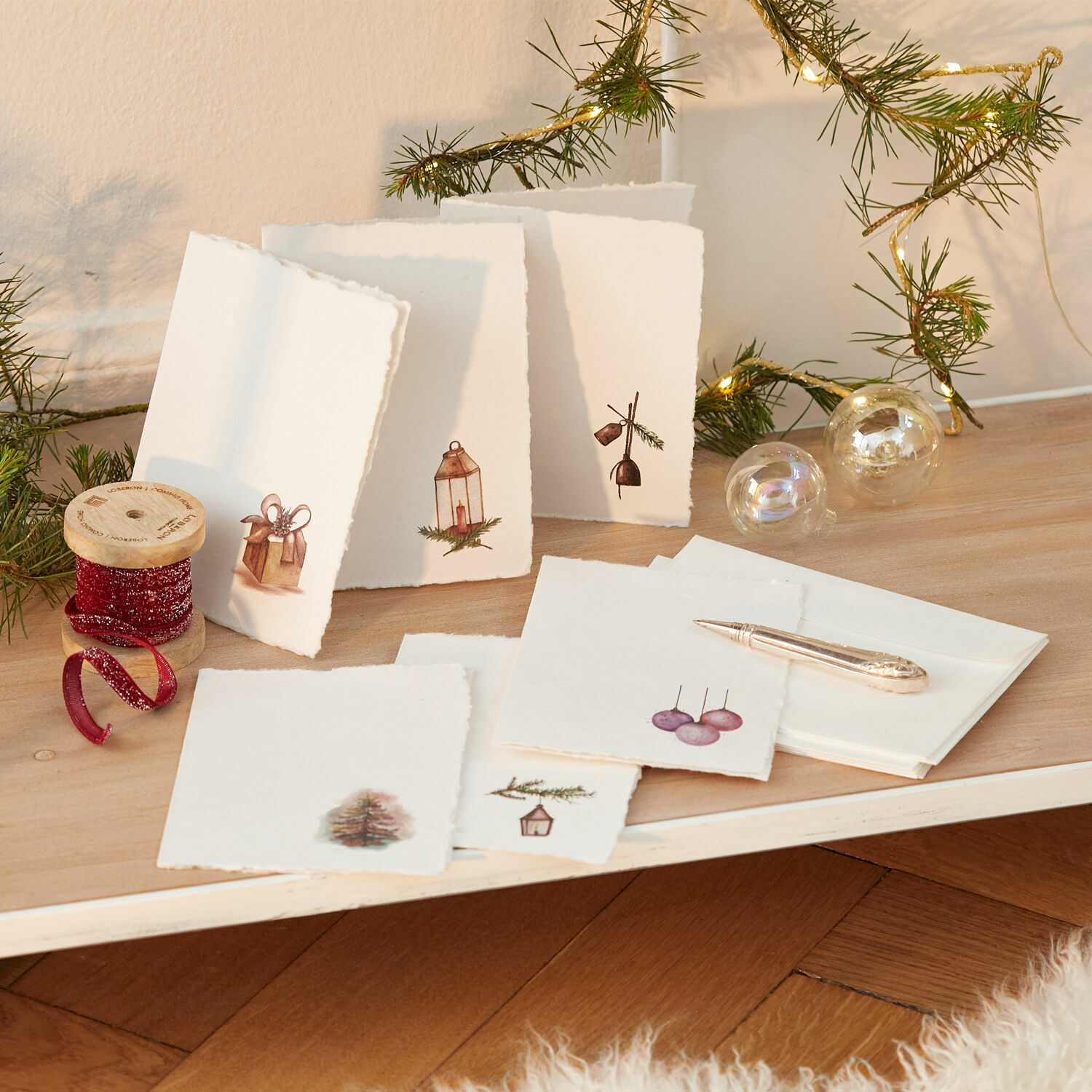 Grusskarten 6er Set Aeloria Set handgefertigter Weihnachtskarten aus Papier mit festlichen Motiven und rotem Dekoband auf Holztisch