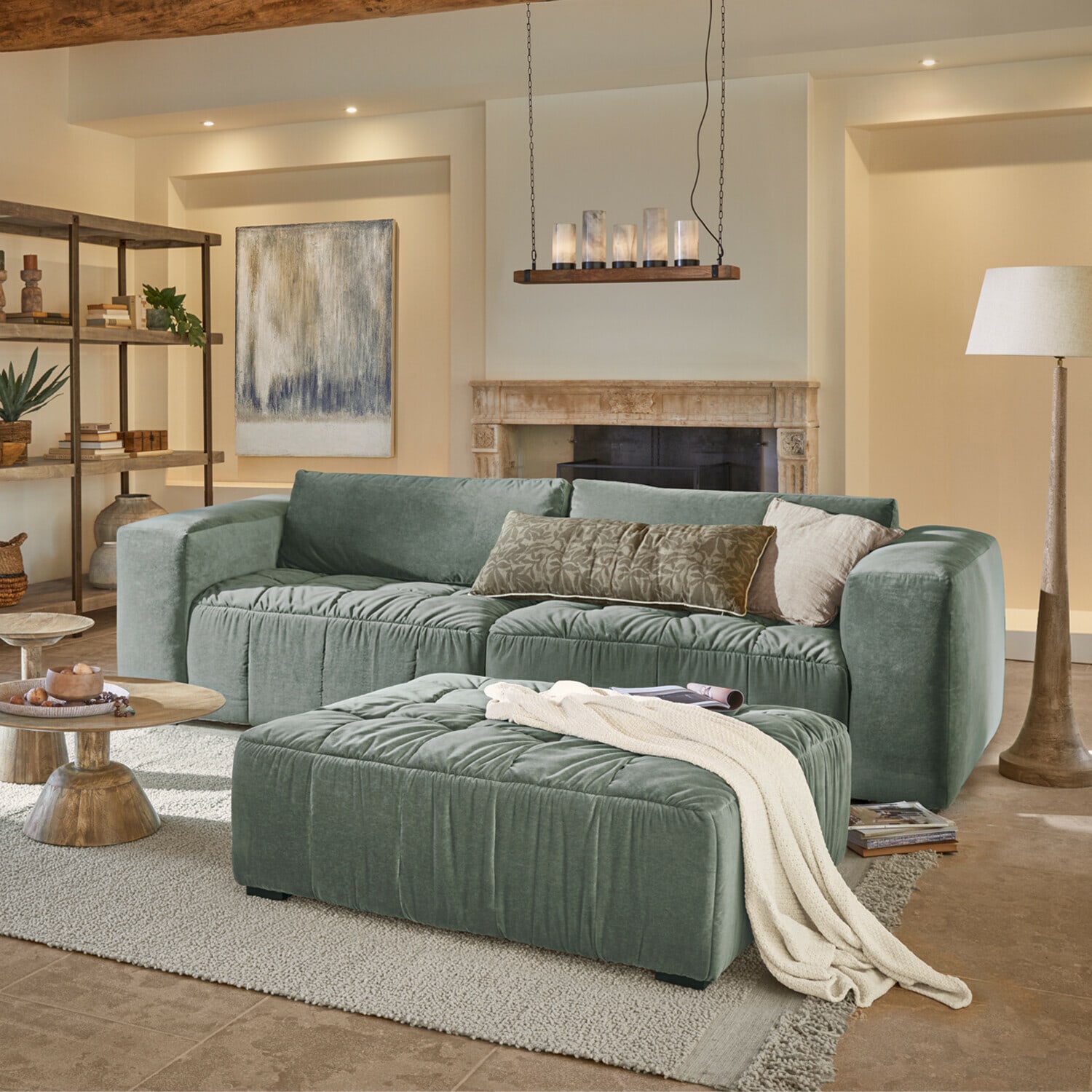 Sofa Ottolline Grünes Samtsofa mit Kissen und Hocker in gemütlichem Wohnzimmer mit Kamin und Stehlampe