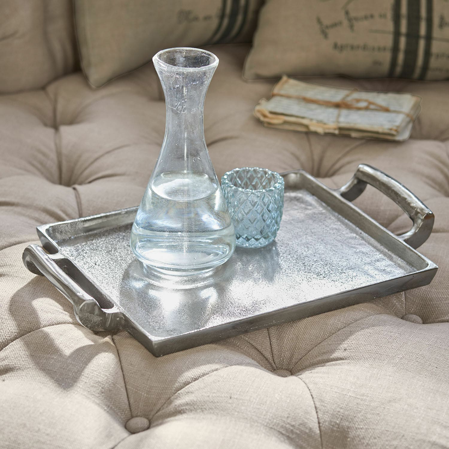 Tablett Connaire Dekoratives silbernes Metalltablett auf beiger, gesteppten Polsterung mit Glas-Karaffe und Becher