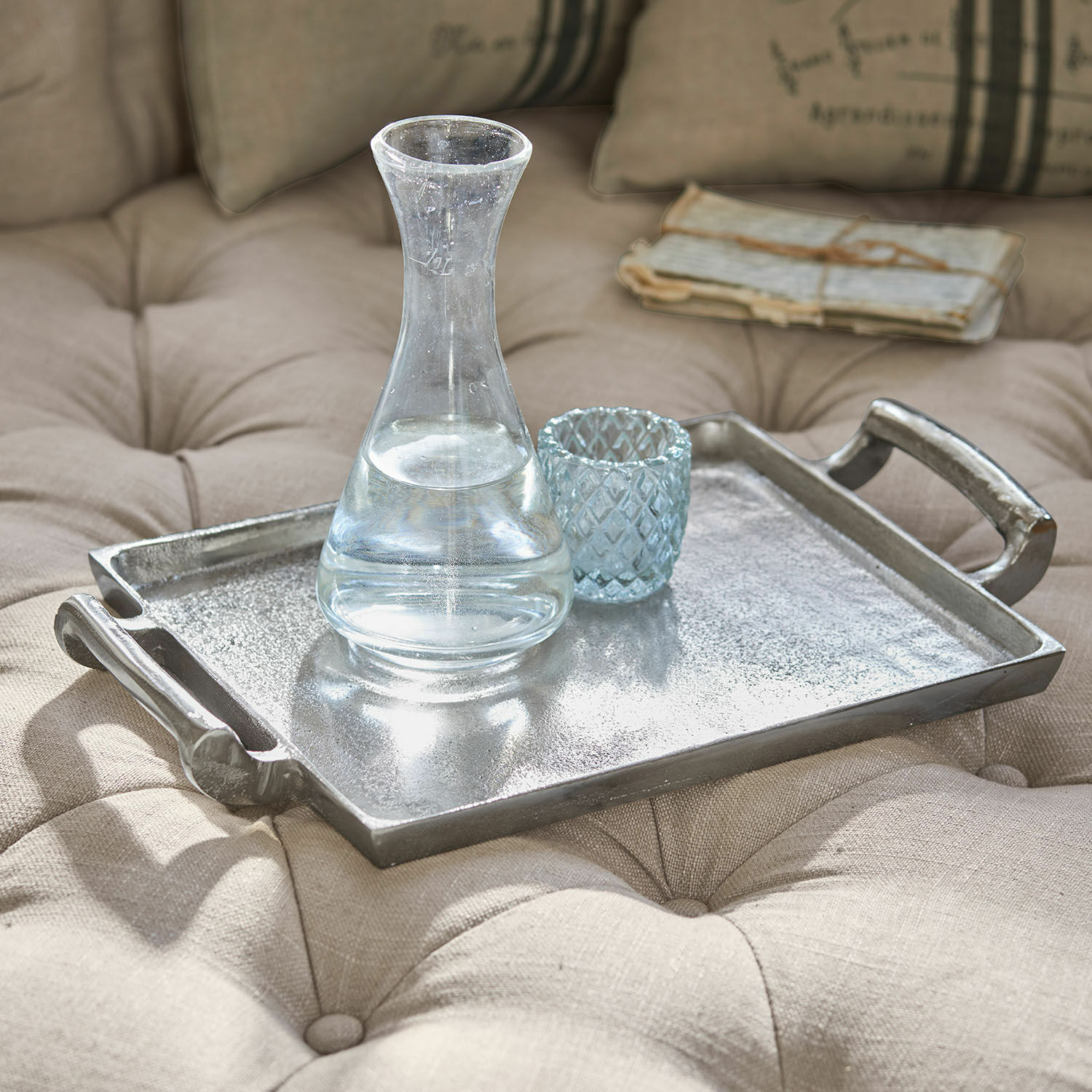 Tablett Connaire Dekoratives silbernes Metalltablett auf beiger, gesteppten Polsterung mit Glas-Karaffe und Becher