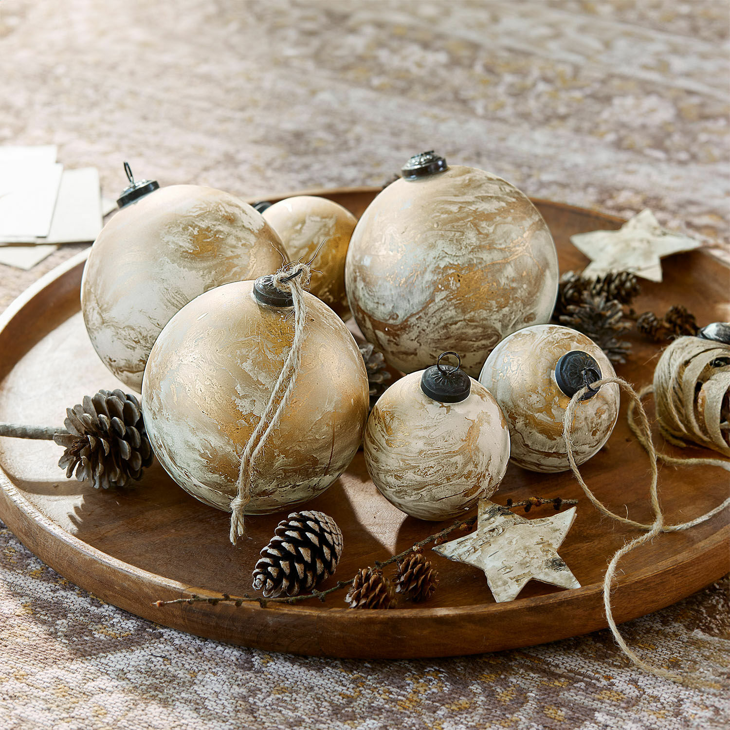 Weihnachtskugel 6er Set Nymeria Set gold-beiger Weihnachtskugeln mit natürlichen Zapfen auf dekorativem Holztablett