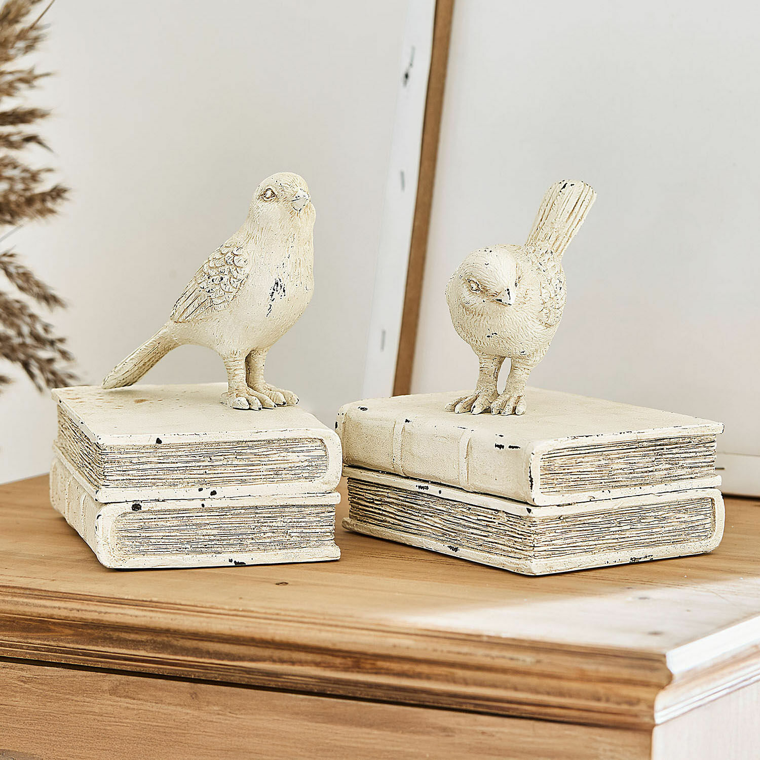 Deko-Figur 2er Set Moonlet Dekorative Vogelfiguren aus cremefarbenem Material auf einem Bücherstapel auf einer Holzplatte