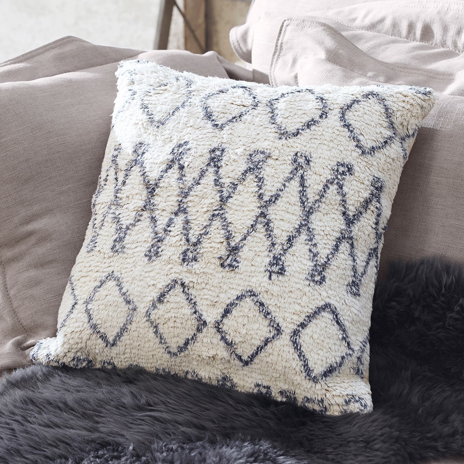 Dekoratives Kissen aus weichem Material in Creme mit schwarzem geometrischem Muster