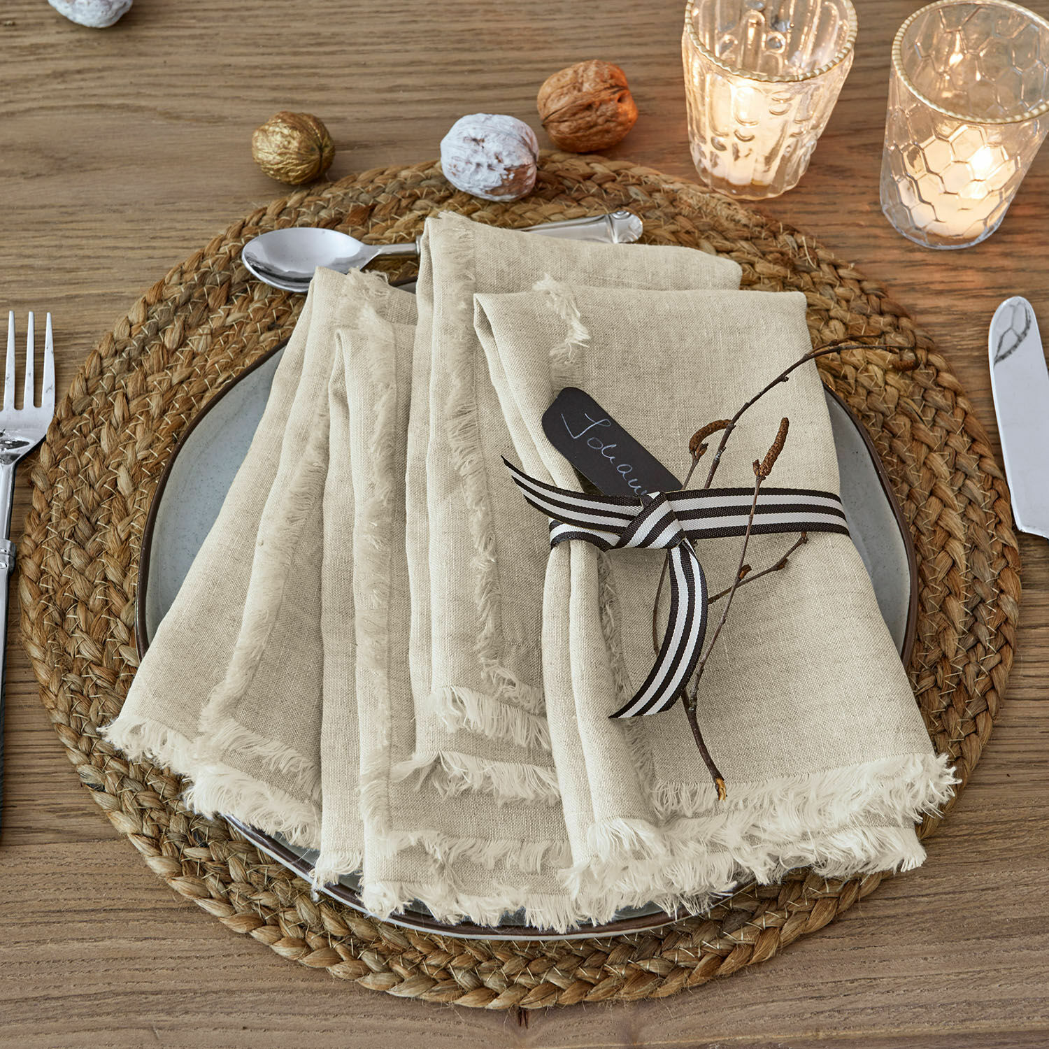Serviette 4er Set Largo Beige Leinenservietten mit Fransen auf einem geflochtenen Platzset aus Holz mit weihnachtlicher Dekoration