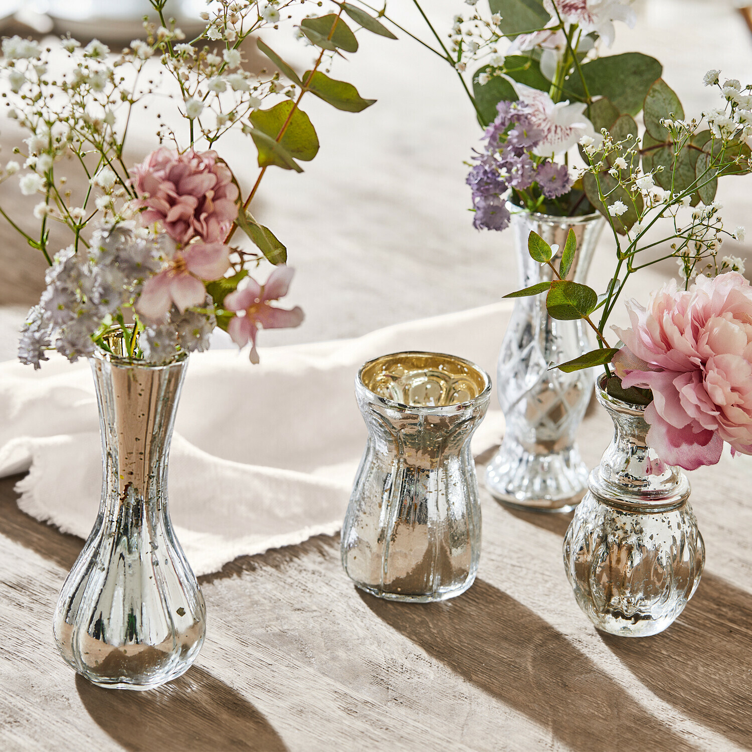 Deko-Vase 4er Set Maelie Vier silberne Glasvasen mit Blumen auf einem Holztisch, stilvolle Tischdekoration im Vintage-Stil