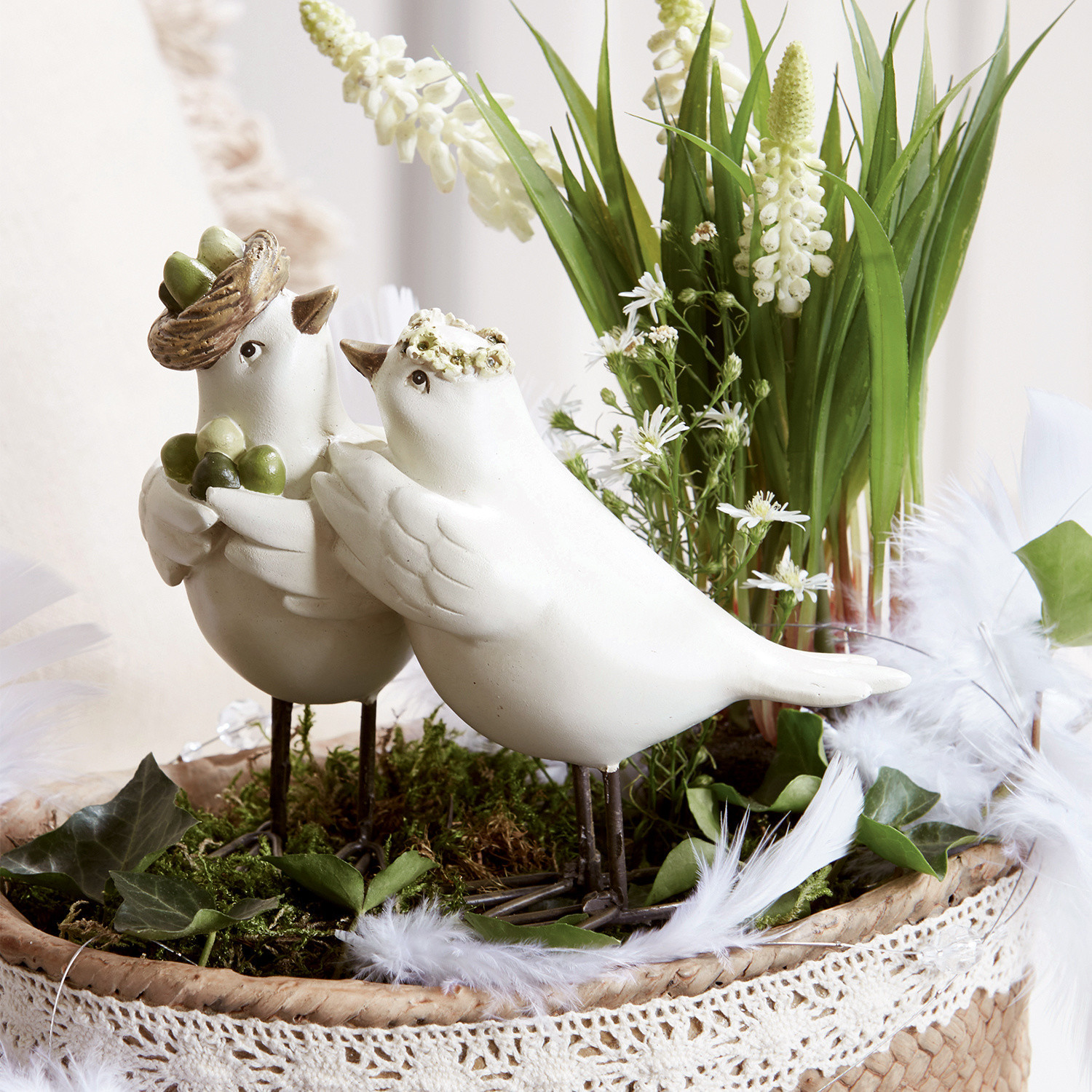 Vogelpaar Orne Weisse Deko-Vögel aus Keramik auf Metallfüssen in einem Korb mit Grünpflanzen und Blumen