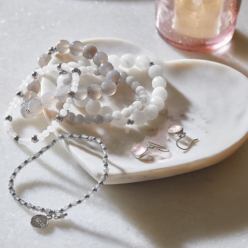 Schmuckset mit weissen und grauen Perlen sowie rosa Ohrringen auf Marmorplatte