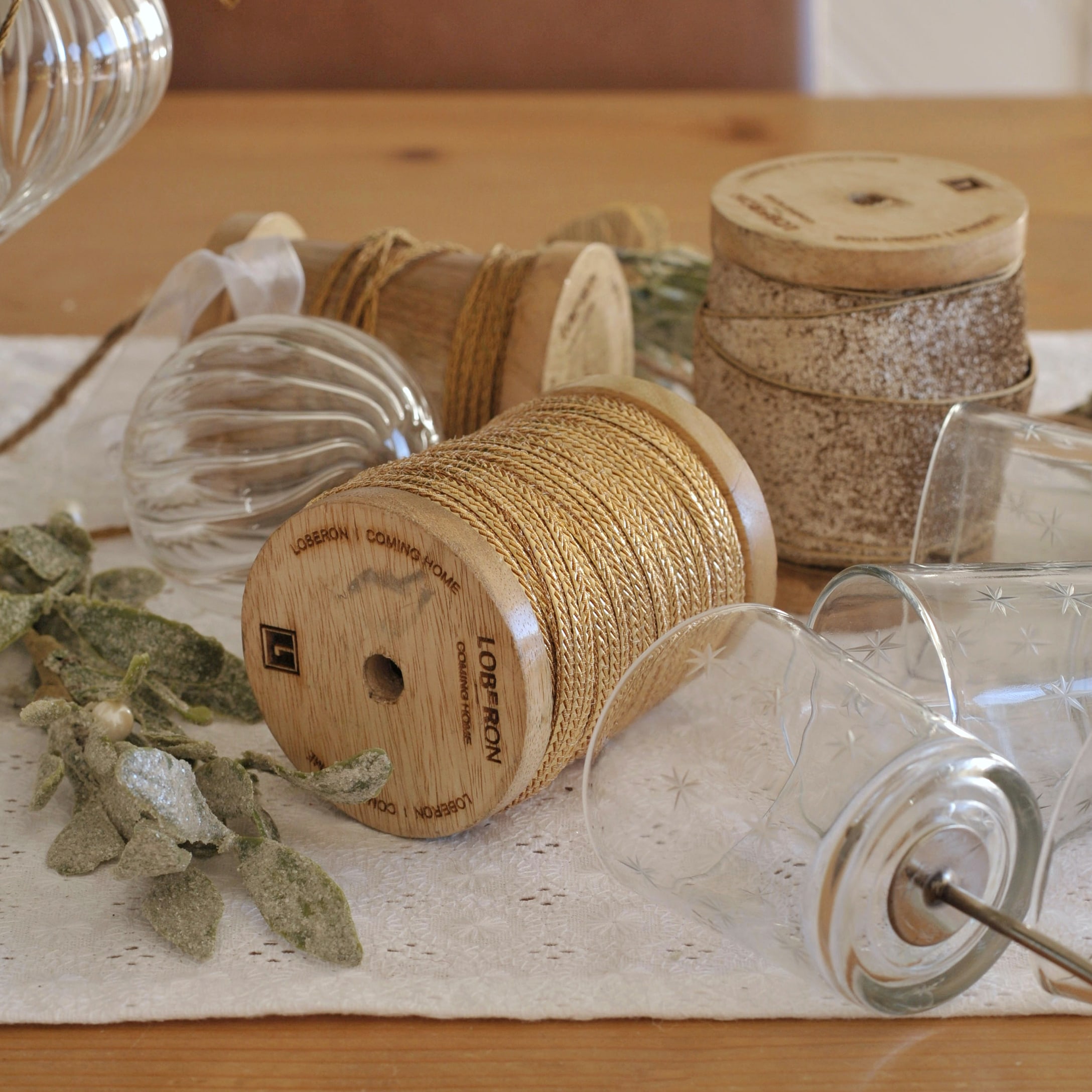 Holzspulen mit Naturkordel und dekorative Glas-Teelichthalter auf festlich gedecktem Tisch