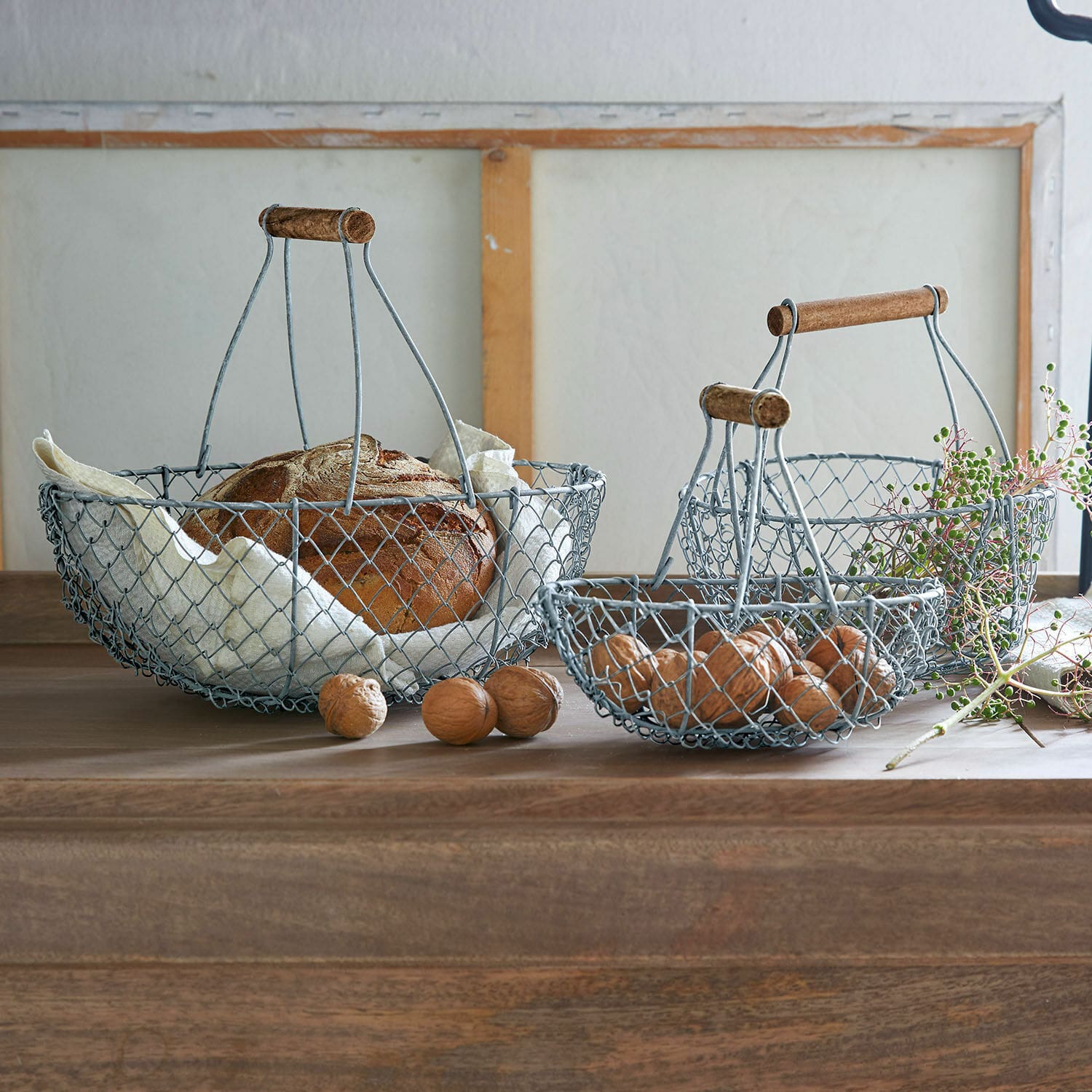 Drahtkorb 3er Set Baker Drei Vintage-Metallkörbe mit Holzgriffen für Brot und Nüsse auf dem Holztisch