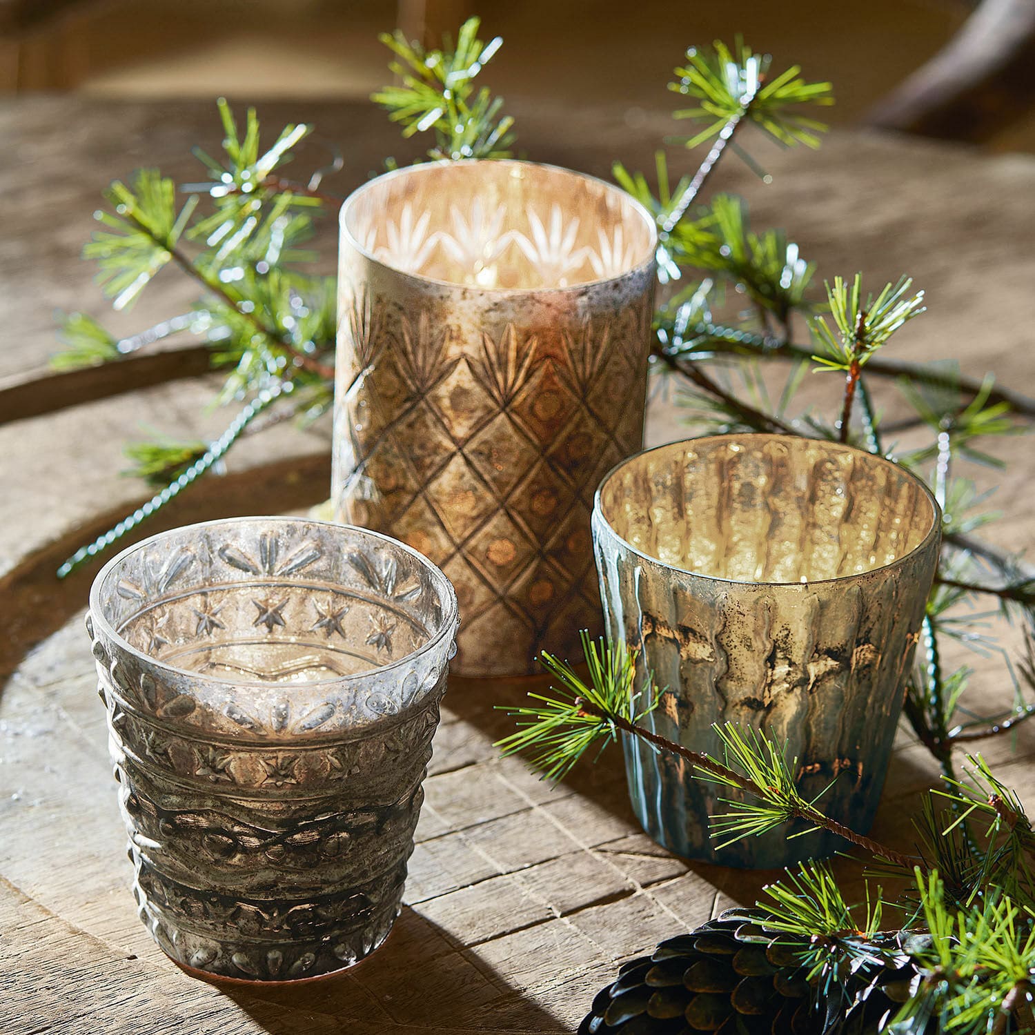 Windlicht 3er Set Ginai Drei dekorative Teelichthalter aus Glas in Braun- und Grautönen mit Muster auf einem Holztisch
