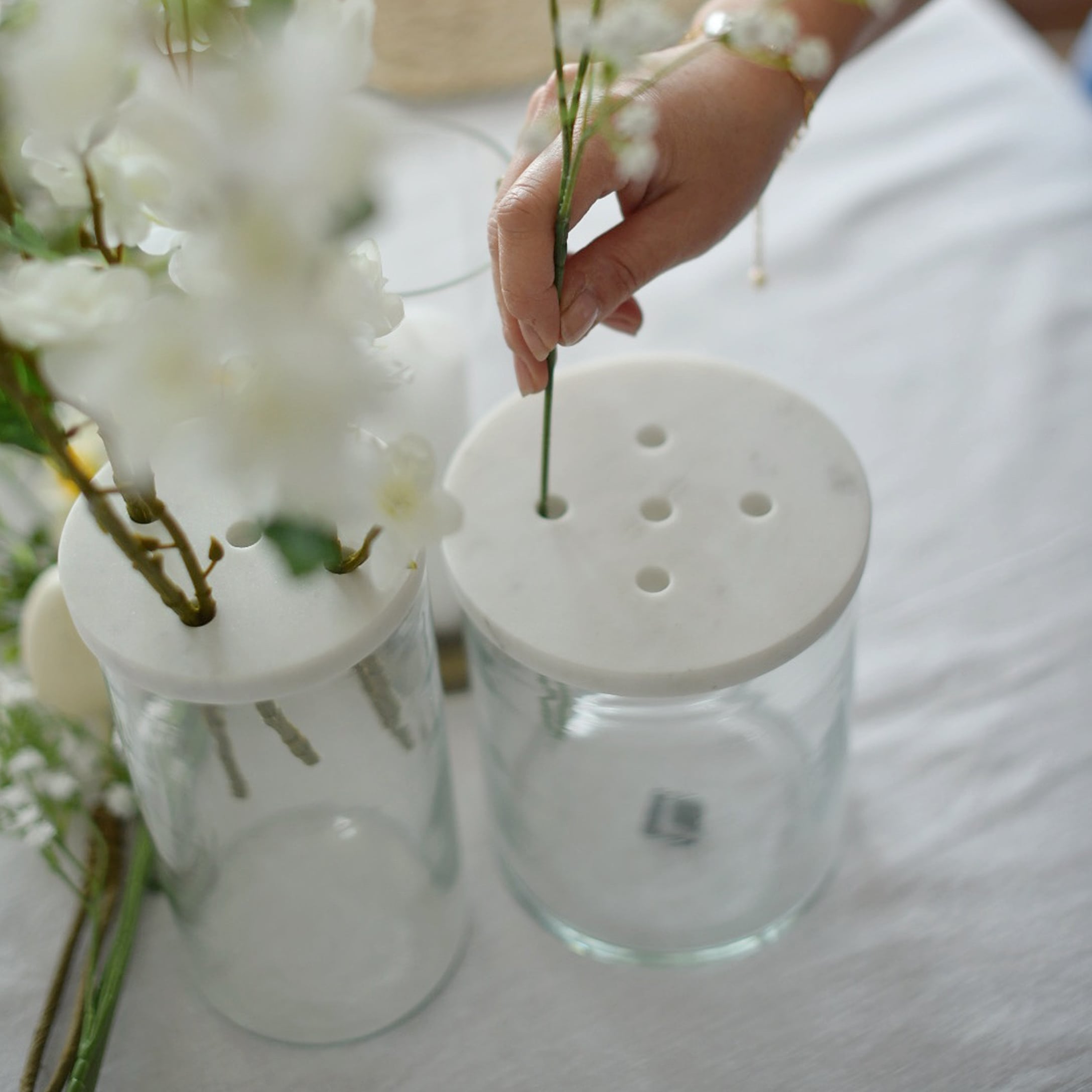 Glasvase mit weissem Marmordeckel und Löchern zum Blumenarrangieren auf dem Tisch