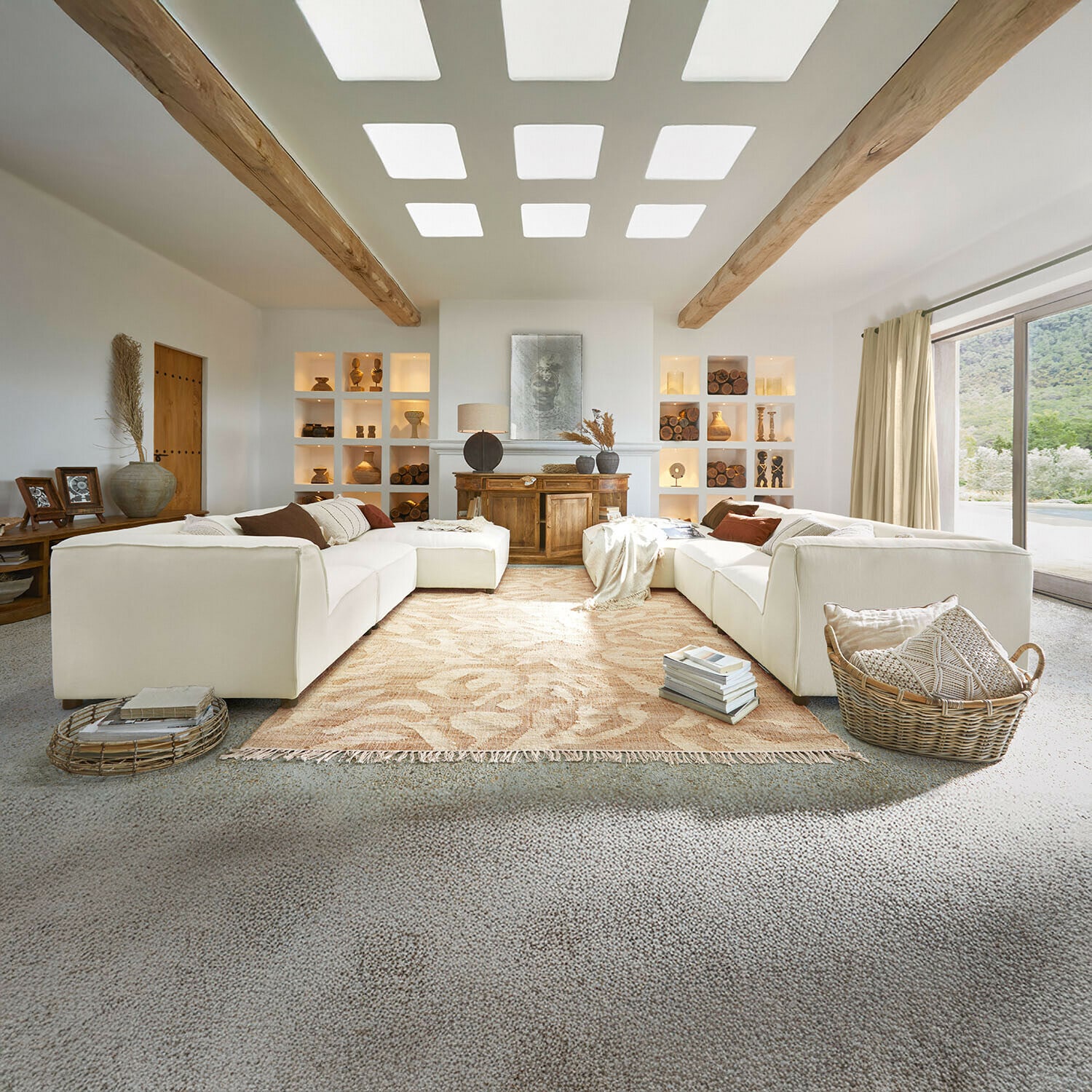 Sofa McLean Großzügiges Wohnzimmer mit weissem Sofa, Holzbalken, Naturdekorationen, beigem Teppich und grossem Fenster