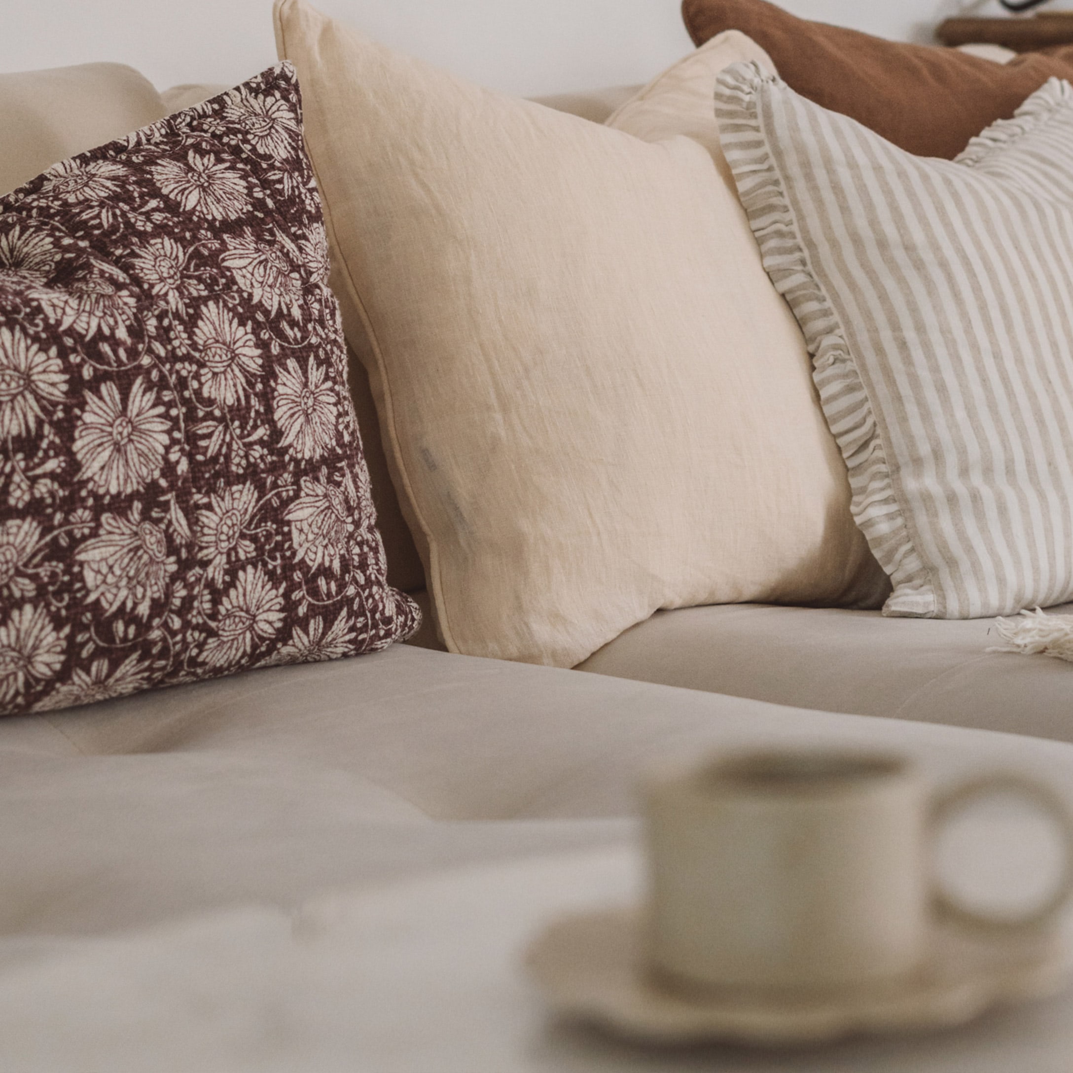 Dekorative Kissen in Beige- und Brauntönen auf hellem Sofa im Wohnzimmer