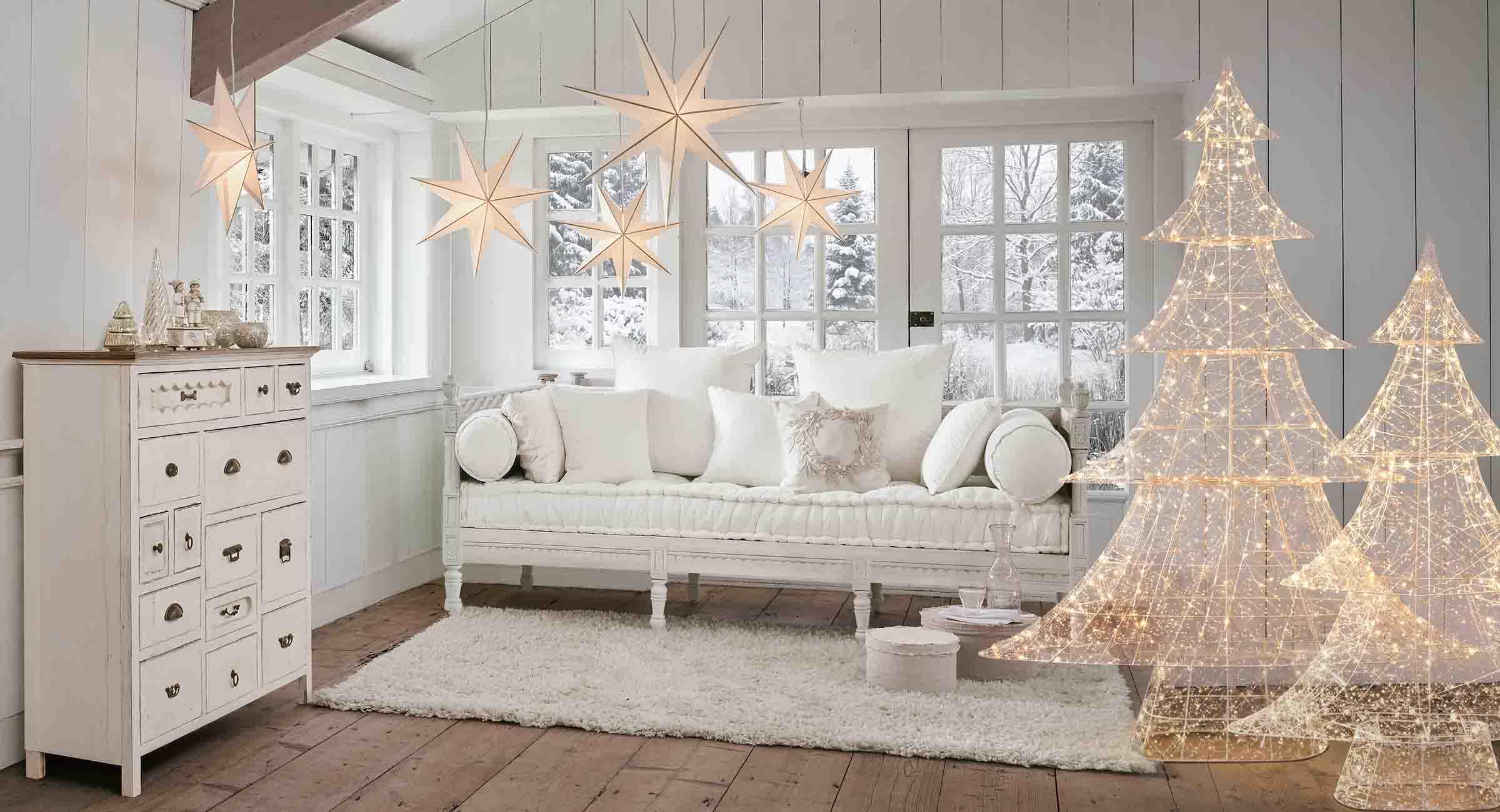 Gemütliches weisses Wohnzimmer mit leuchtenden Stern- und Tannenbaum-Dekorationen für den Winter