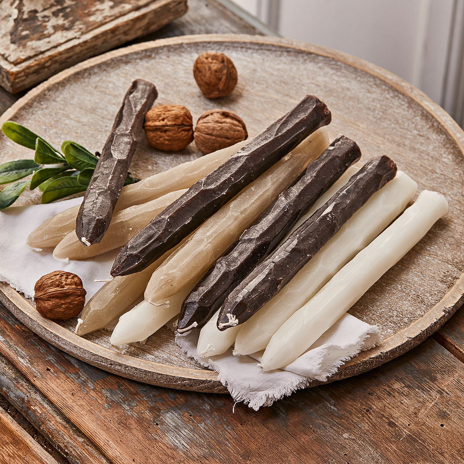 Kerze 12er Set Savineau Set mit weissen, beigen und braunen Tischkerzen auf Holztablett mit dekorativen Walnüssen